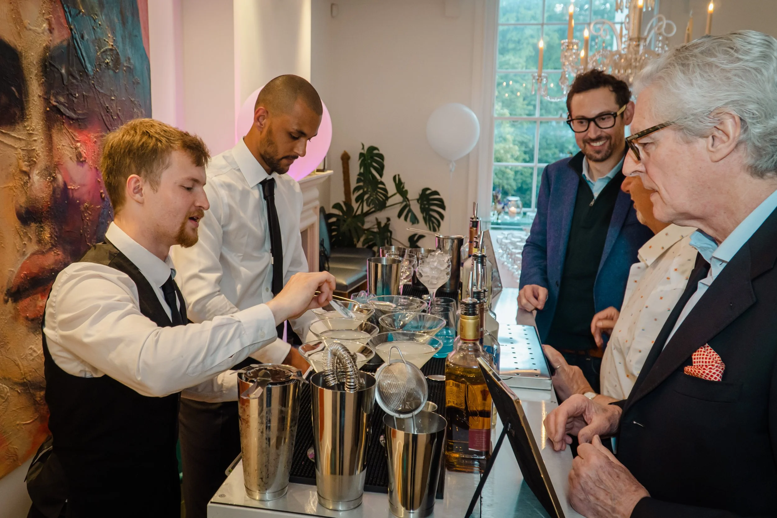 Bartender for private event London helping guests choose personalised signature cocktails.