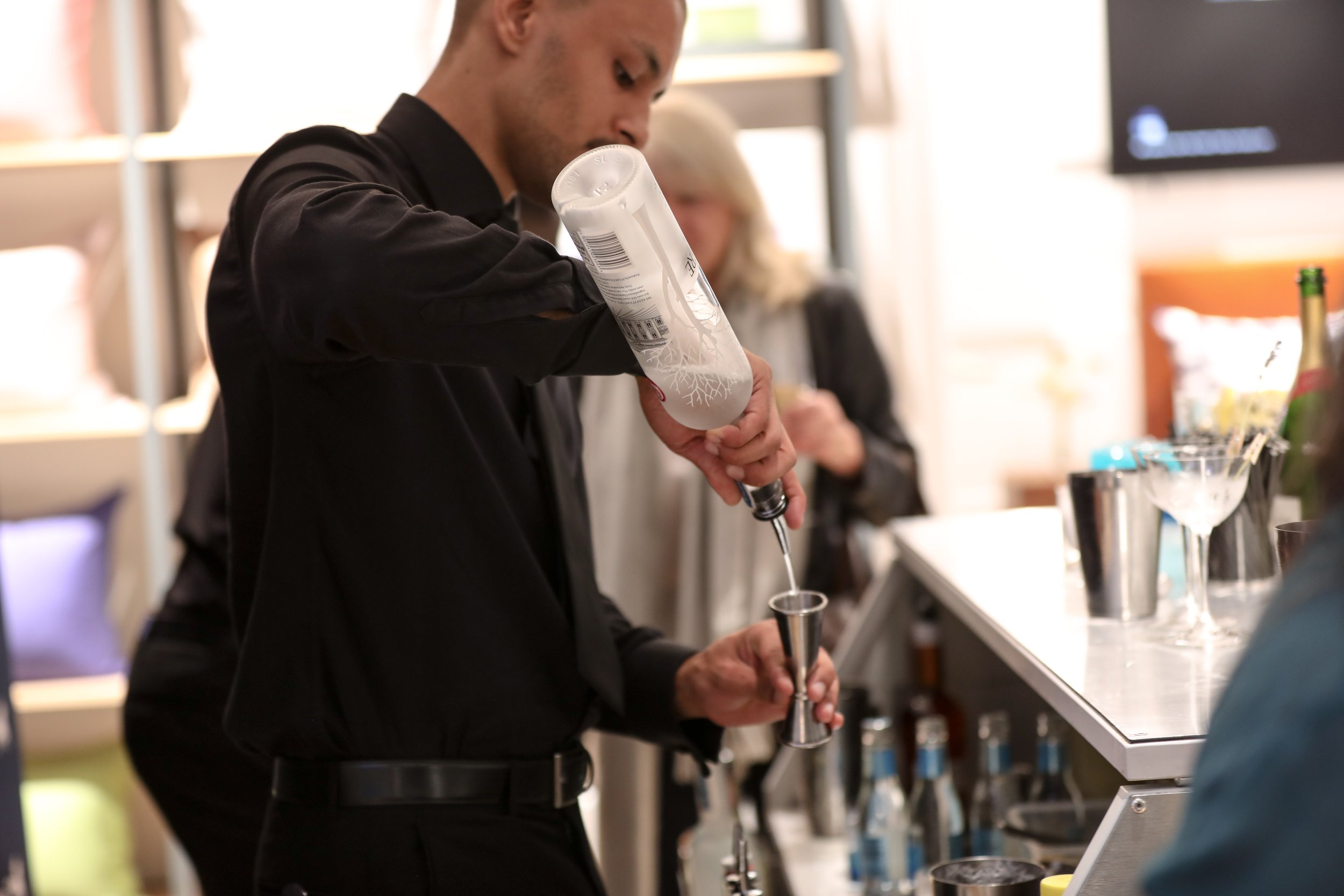Corporate mixologist creating signature cocktail at luxury brand launch event in London.