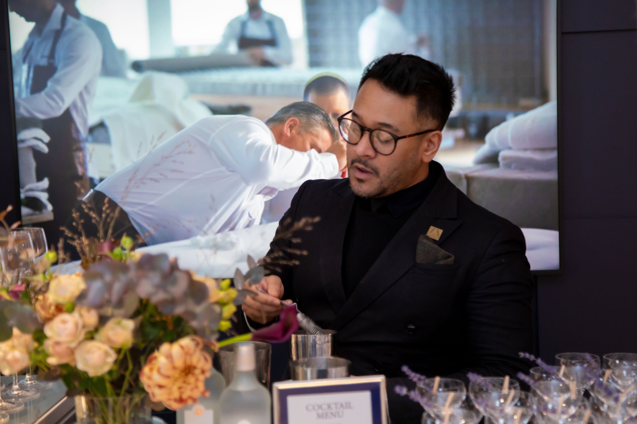 Corporate mixologist managing a busy service period calmly at a professional networking event.