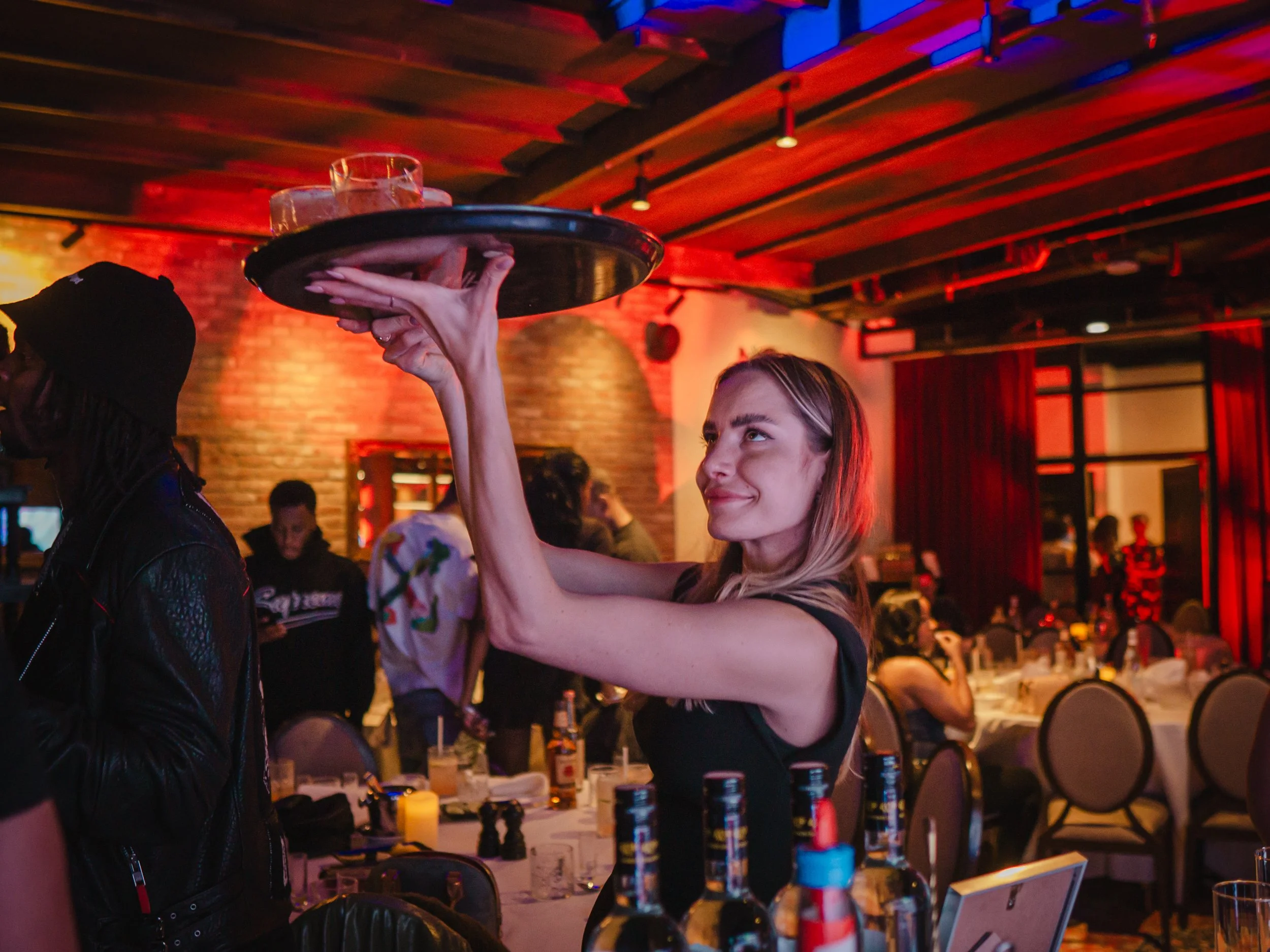 Butler-style cocktail service at home with private mixologist creating luxury house party atmosphere.