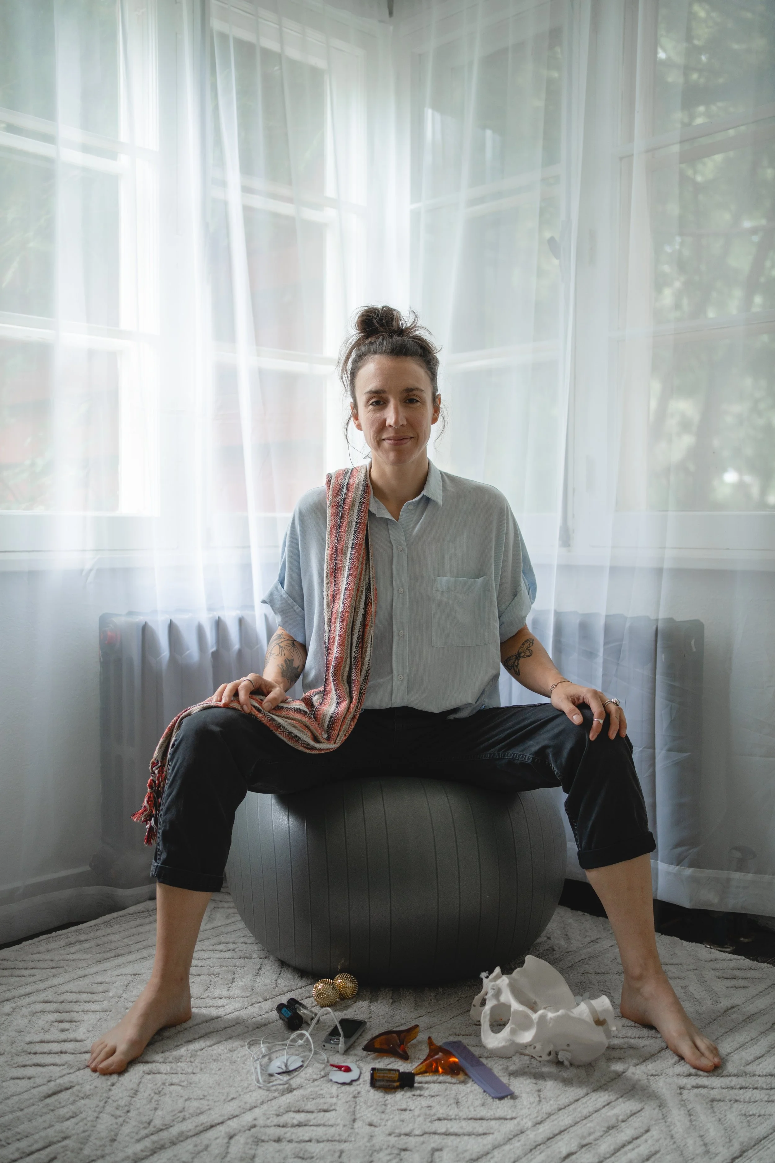 Photographie de Marie-Claude assise sur un ballon de naissance avec des accessoires de Doula.