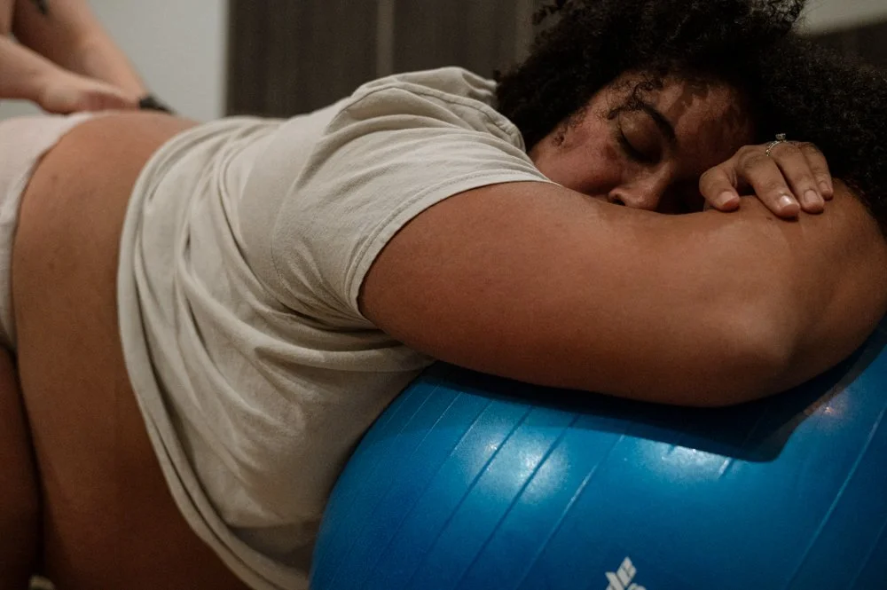 Femme reposant sa tête sur un ballon de fitness bleu dans une pièce cosy.
