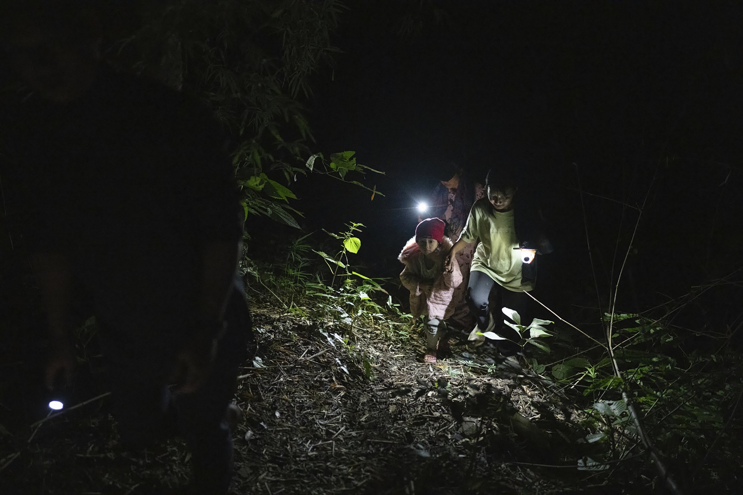 Karenni refugees crossing into Thailand by night. Myanmar, 2023