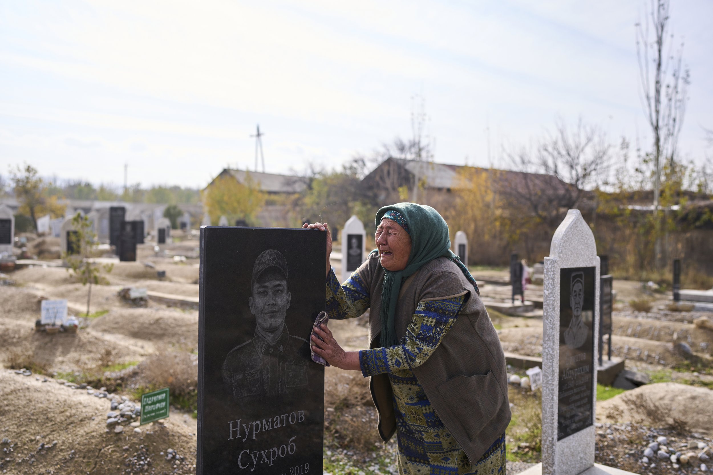 Woman crying at the grave of her son who was beaten to death by fellow conscripts while in the military. Tajikistan, 2022