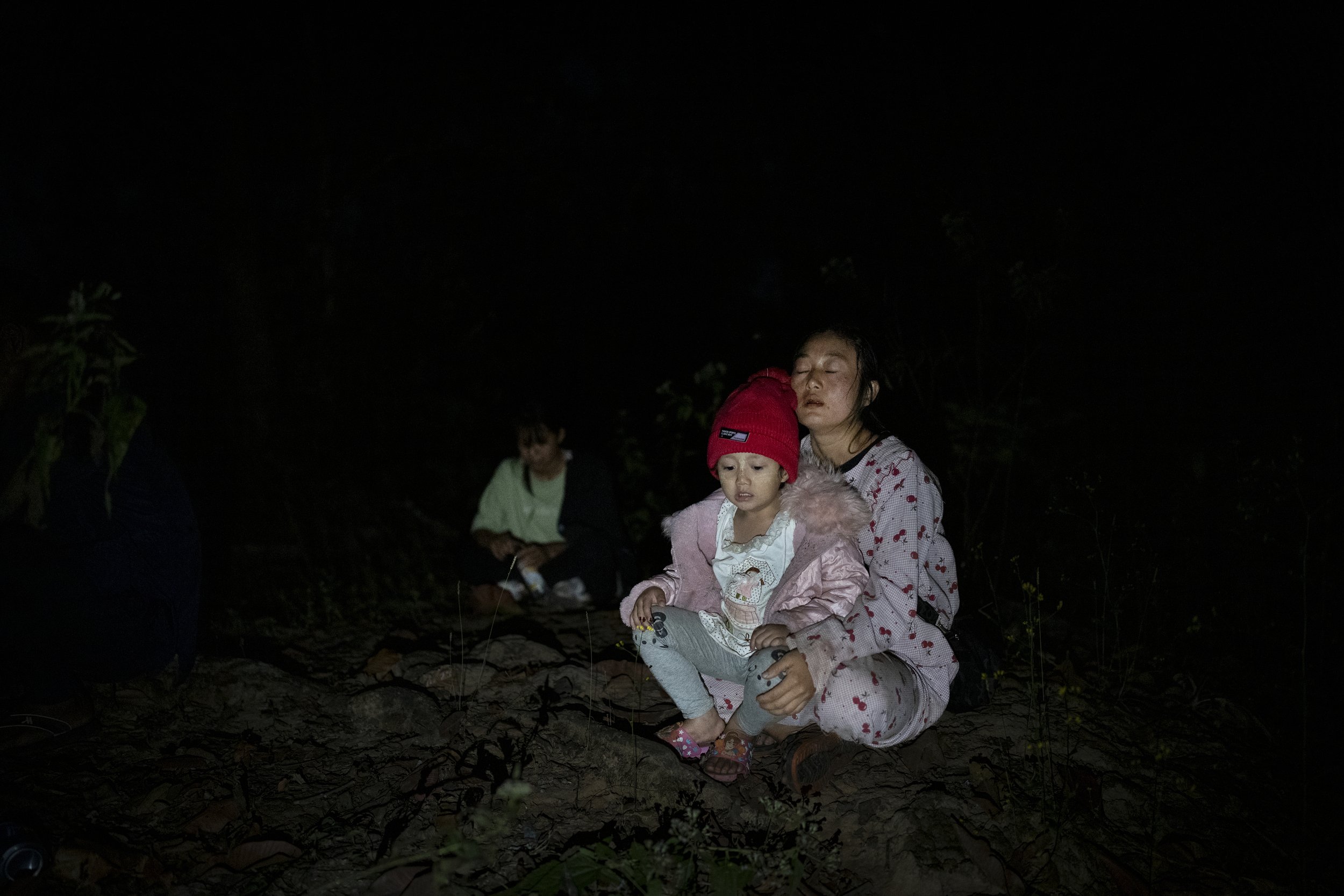 Exhausted mother and her four year old daughter resting. After their village was destroyed, they fled in the middle of night on foot through the jungle into Thailand. Myanmar, 2023
