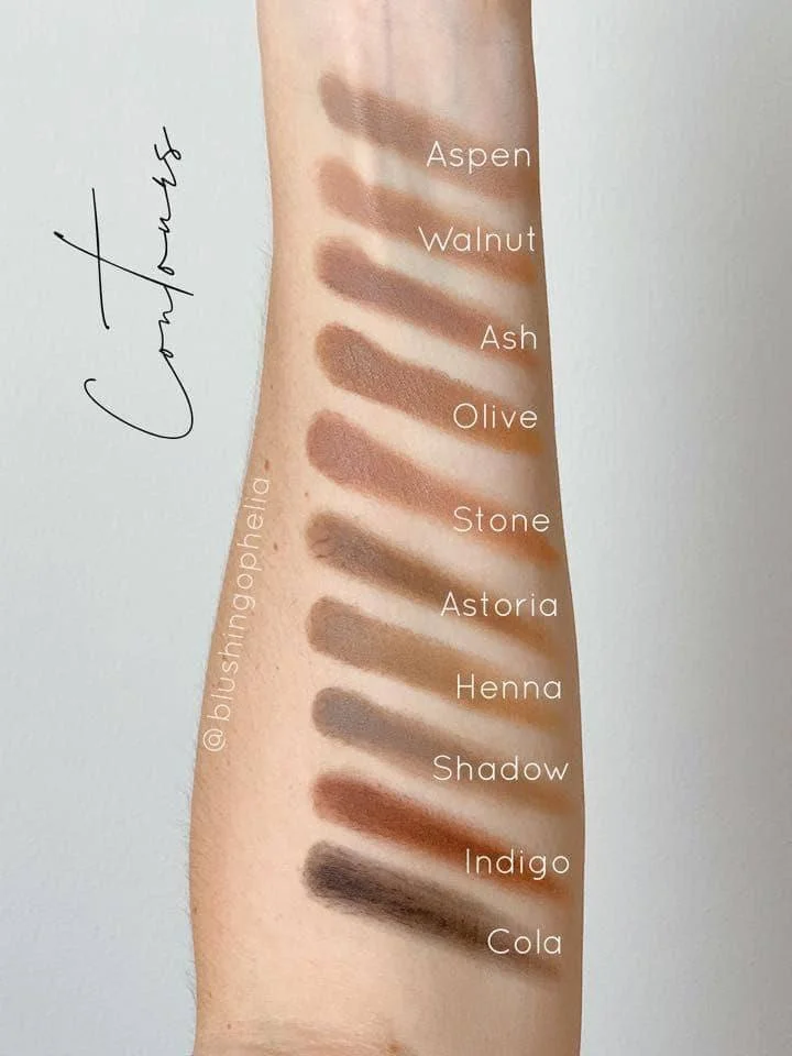Swatch of eyeshadow shades on an inner forearm labeled from top to bottom: Aspen, Walnut, Ash, Olive, Stone, Astoria, Henna, Shadow, Indigo, Cola.