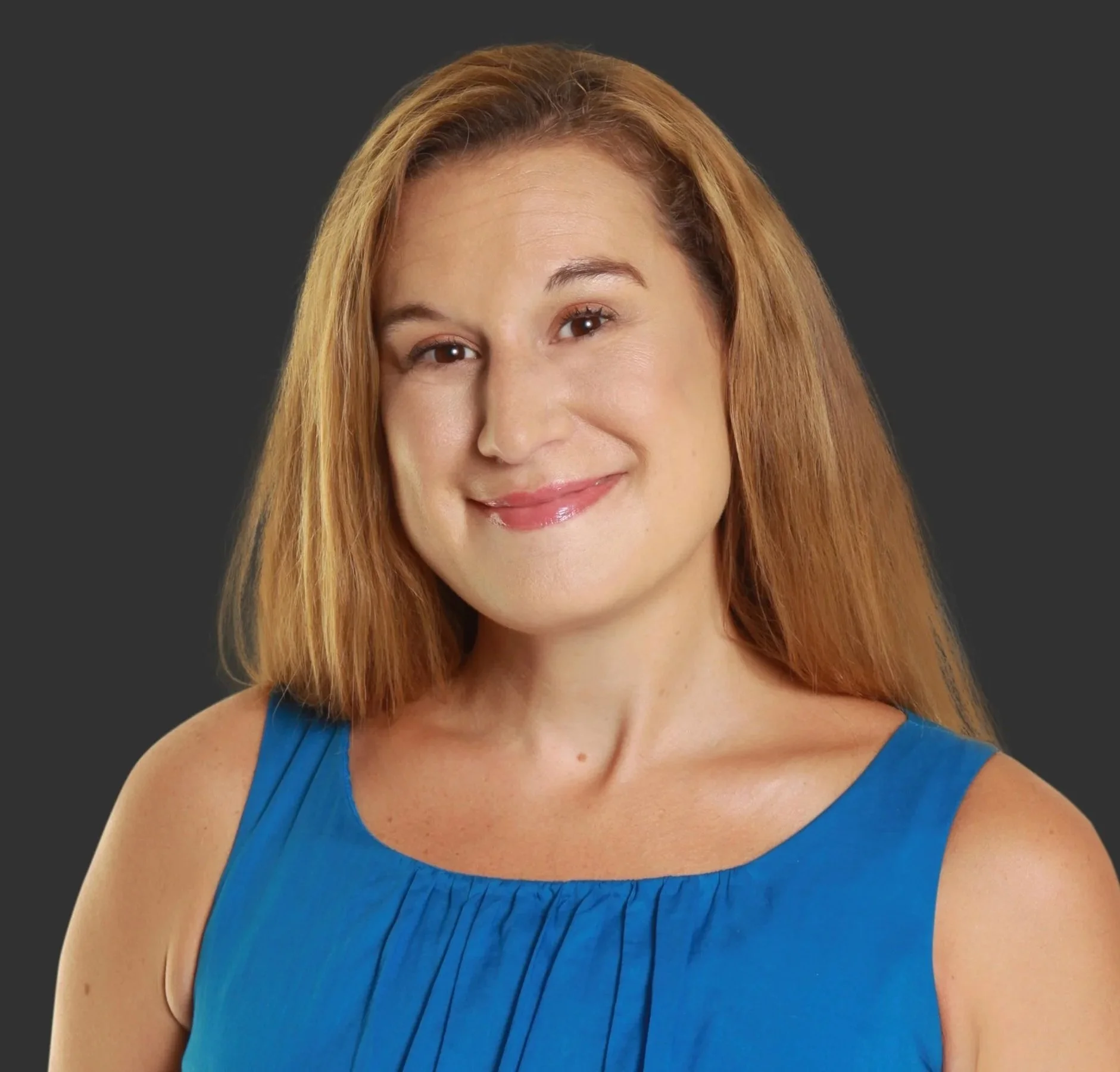 Portrait of a woman with shoulder-length light brown hair wearing a blue sleeveless top, smiling slightly against a dark gray background.