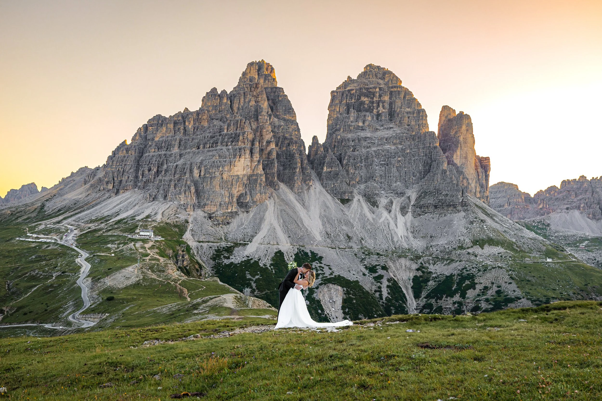 Ein Brautpaar steht vor den Drei Zinnen in den Dolomiten und küsst sich