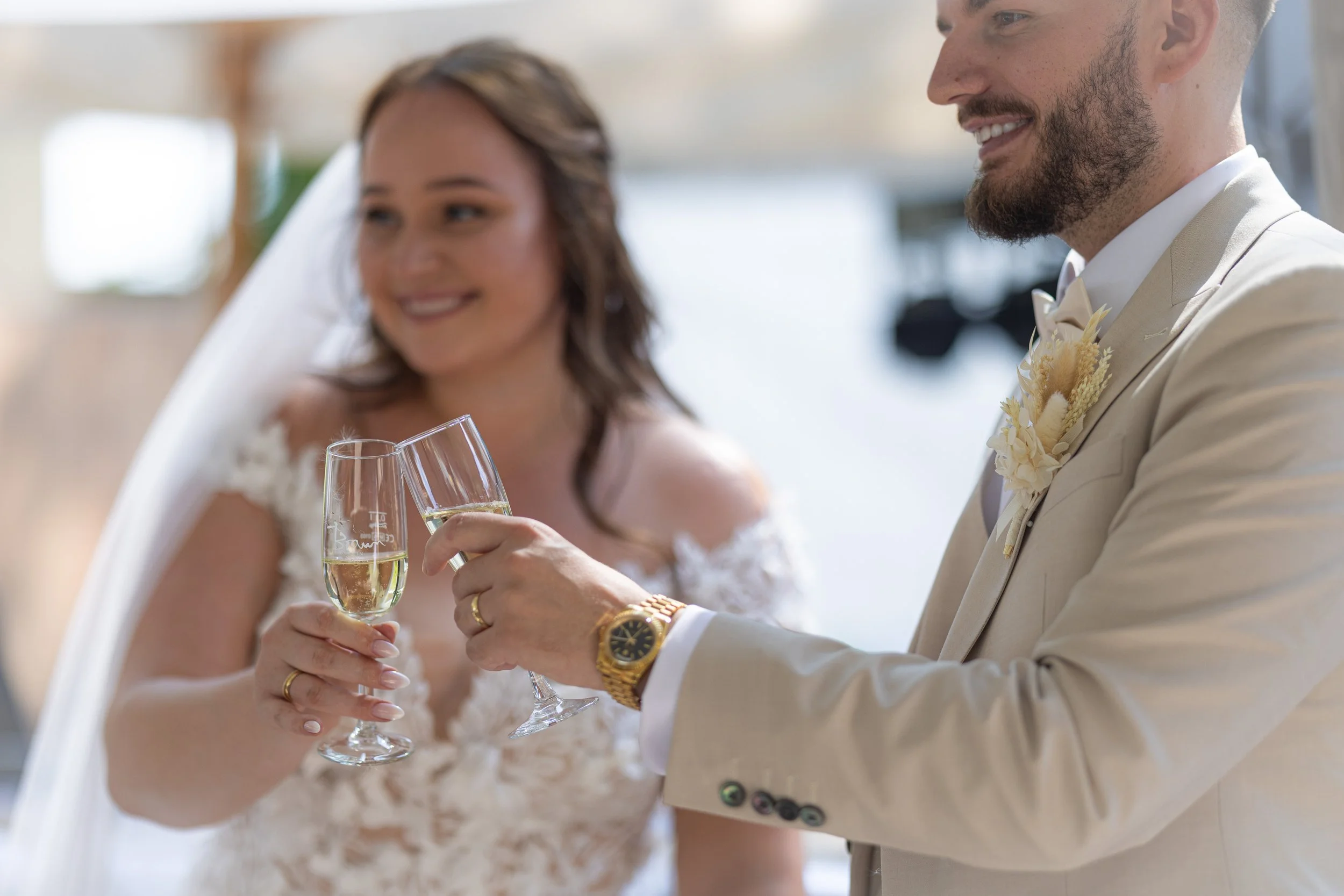 Ein Brautpaar stößt glücklich nach der Trauung am Rheinstrand mit Sekt an.