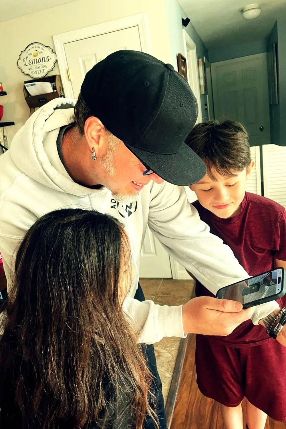 A dad and his kids watching scripture come alive on a phone in their kitchen