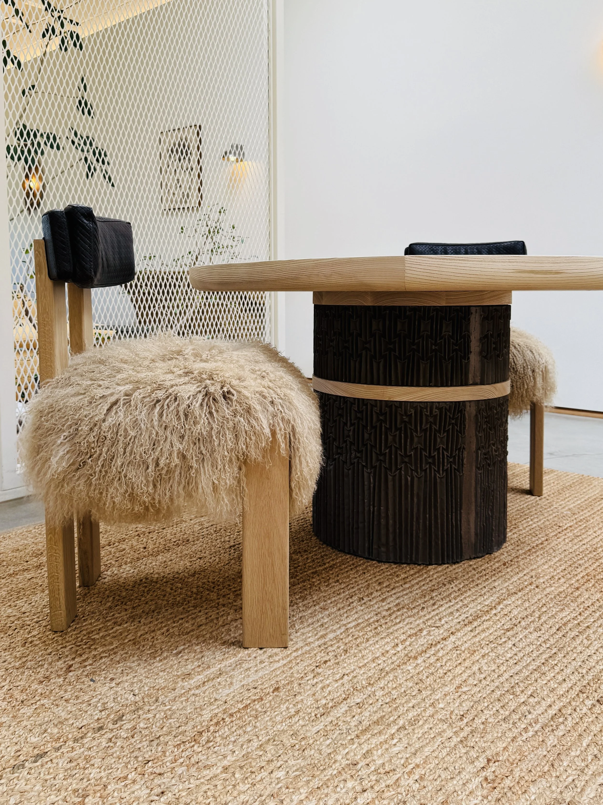 Plinth series of concrete table bases by O.M. Studio. Made from hand-scored pleating fabric paper. Dining table and chairs at Stahl + Band, Los Angeles.