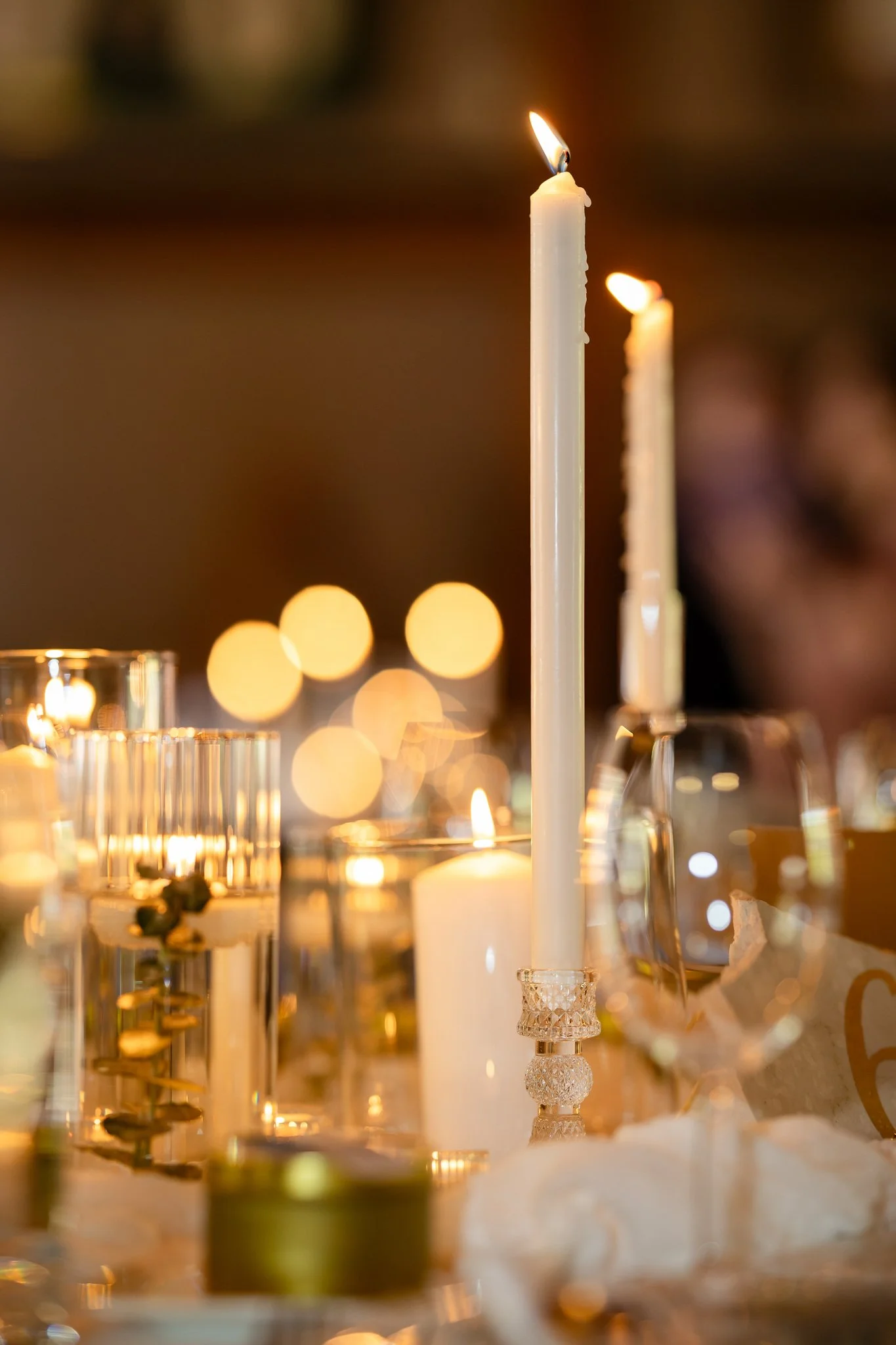 A close-up of lit candles on a decorated table for a celebration or formal event.