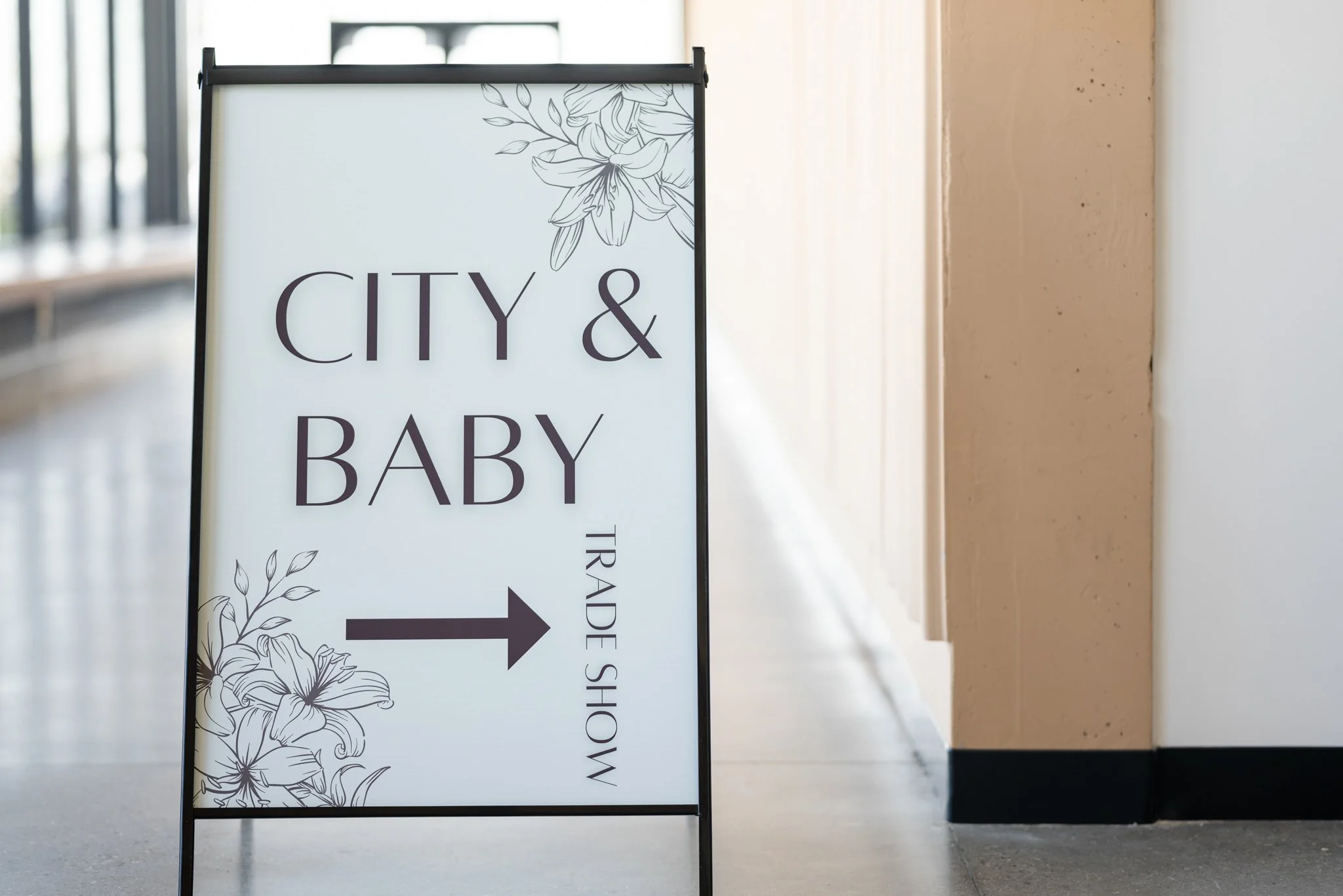 Signboard indicating trade show for baby and city items with an arrow pointing right.