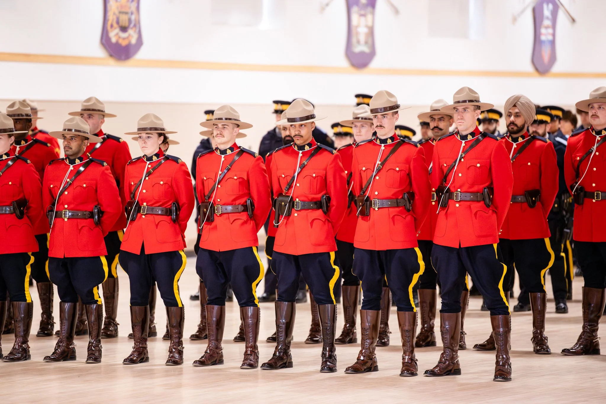 A group of Canadian Mounties in red uniforms and tan hats standing in formation during a parade or ceremony.