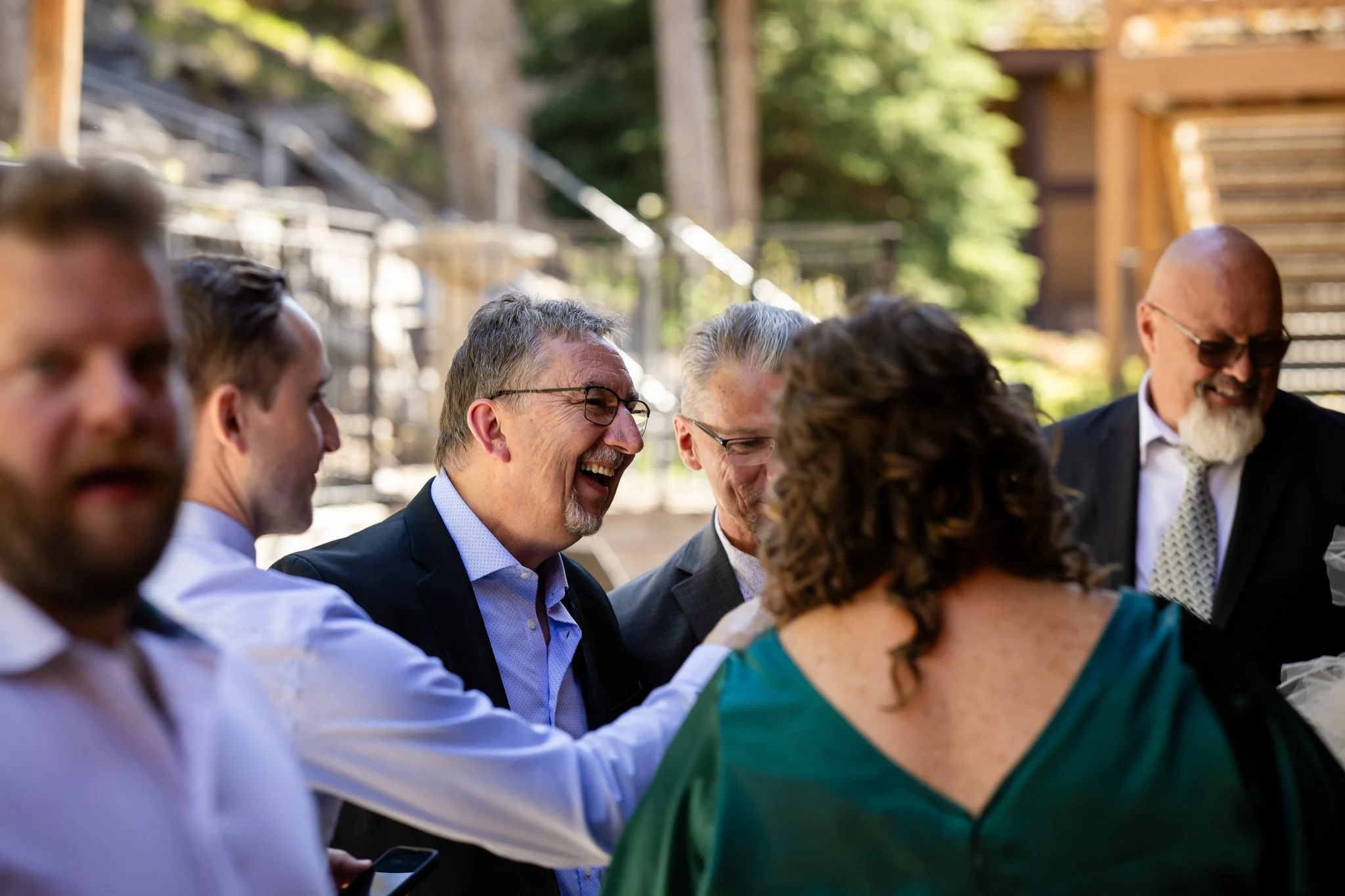 Group of adults smiling and laughing outdoors at a social gathering or event.