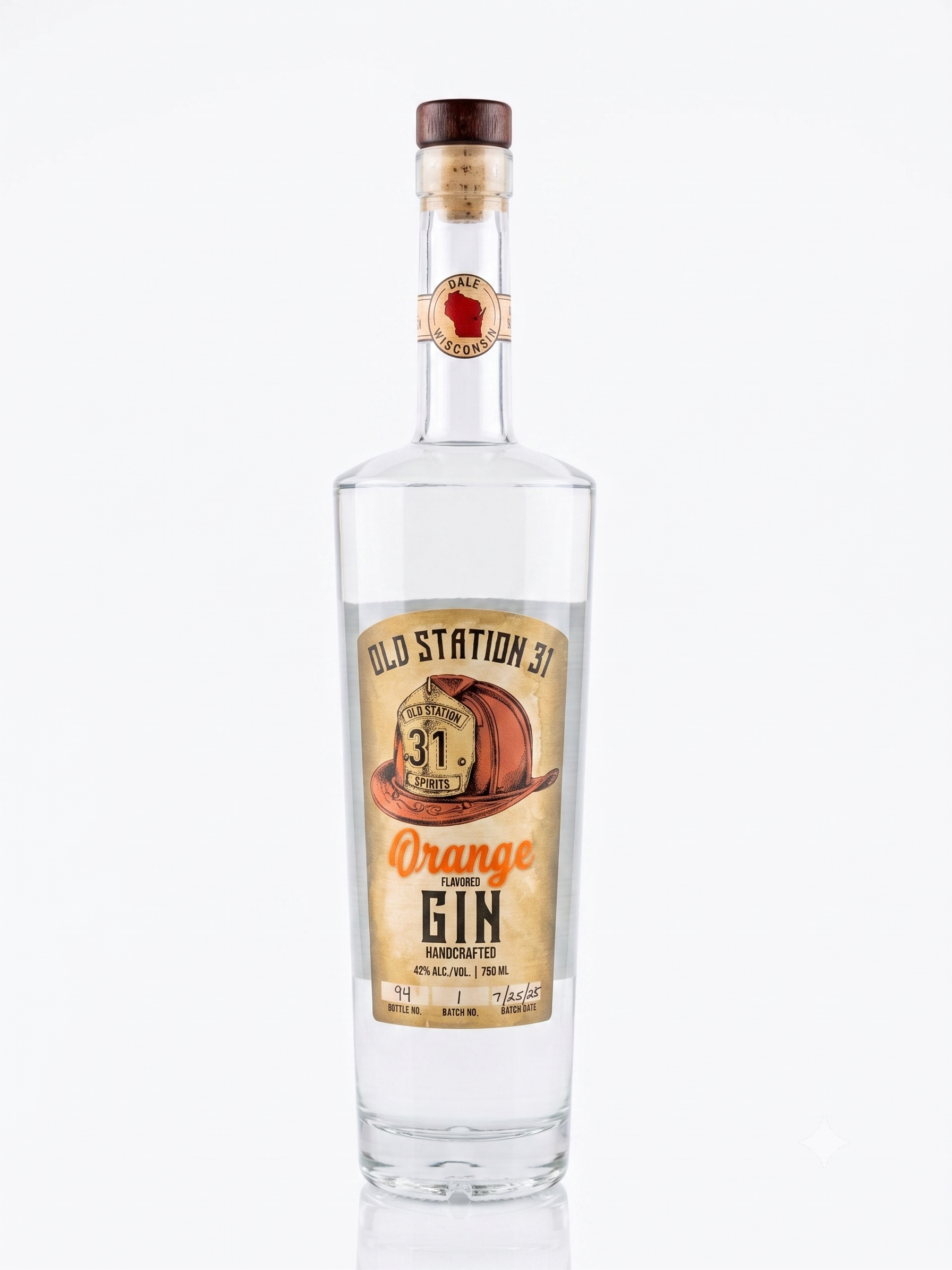 A tall, clear glass bottle of orange flavored gin with a wooden cap and a label from Old Station 31 Spirits. The label features a vintage design with an orange hat and shows details such as alcohol content (42%), volume (750 ml), and batch information.
