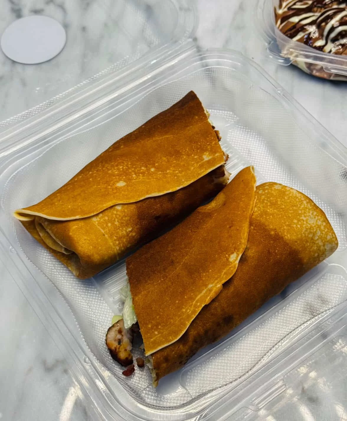Two beef and lettuce burritos in a clear plastic container.