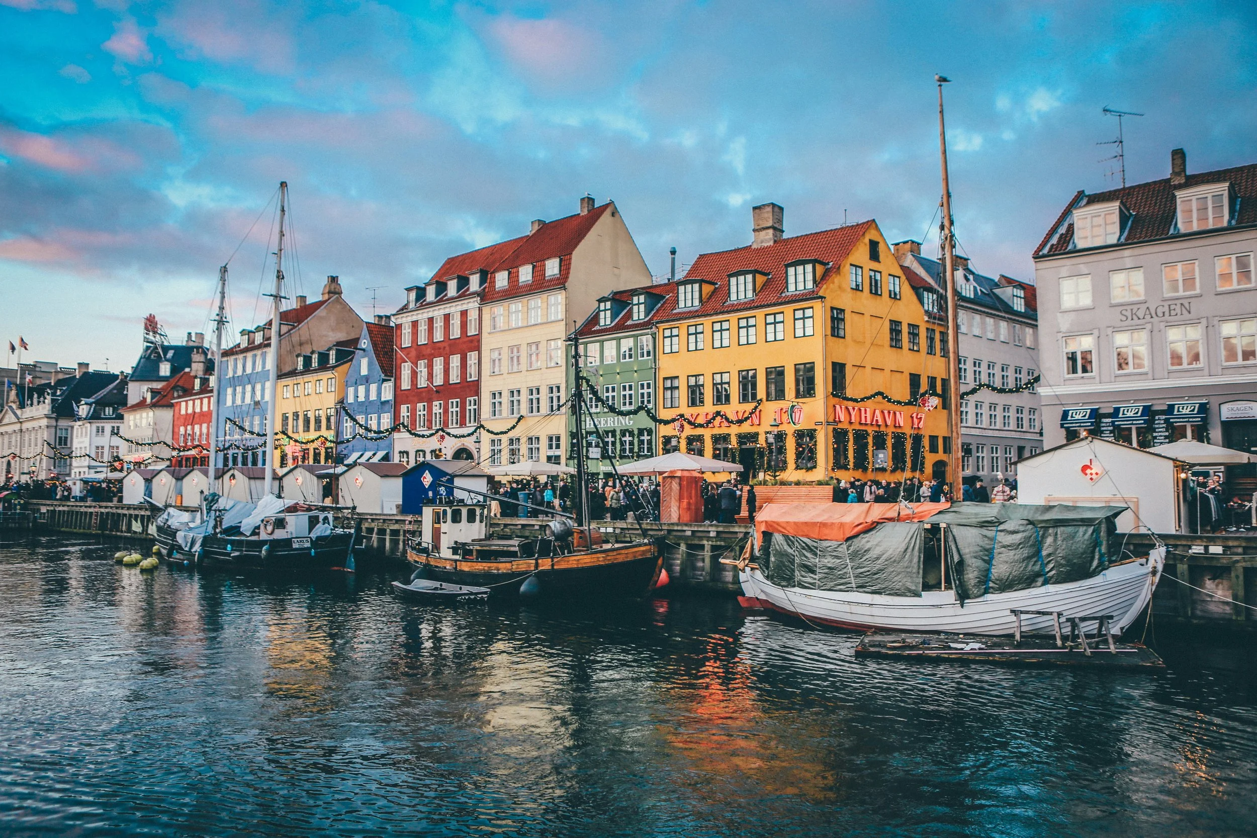 Colorful buildings along the waterfront with boats docked in the canal, at sunset.