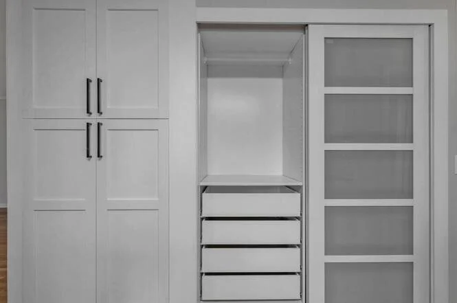 Empty white kitchen cabinet with drawers and sliding glass door.