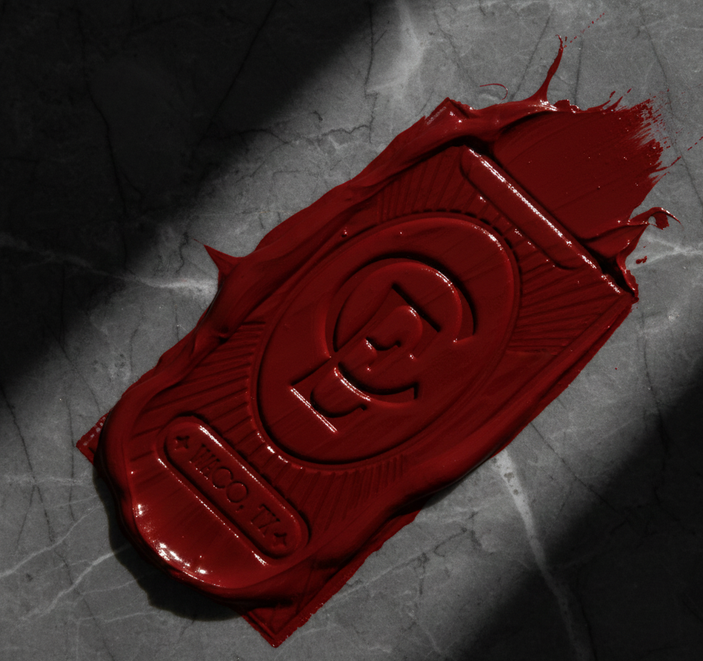 A bar of red soap with an embossed dollar sign and the words 'Money Soap' on it, placed on a dark marble surface.