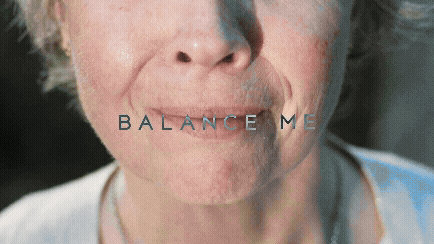 Close-up of an elderly person's face with the words "BALANCE ME" written across their lips.