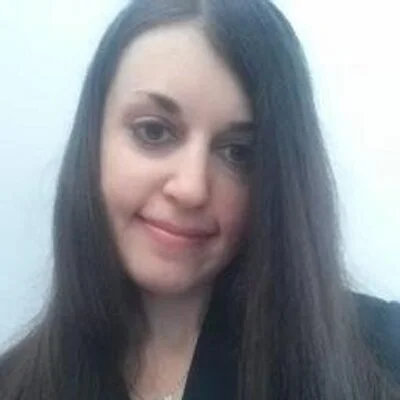 Portrait of a woman with long dark hair smiling at the camera.