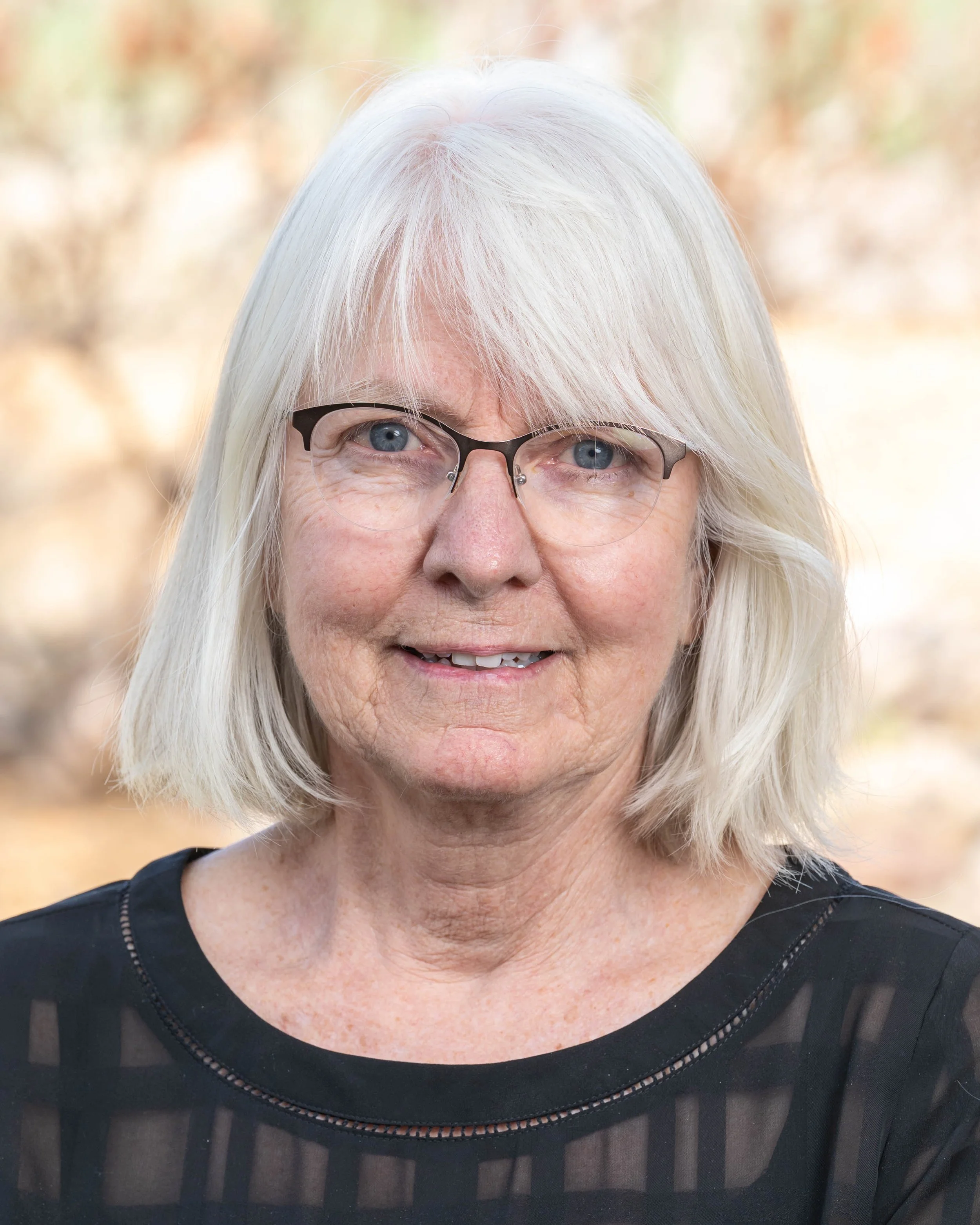 Elderly woman with glasses and necklace outdoors