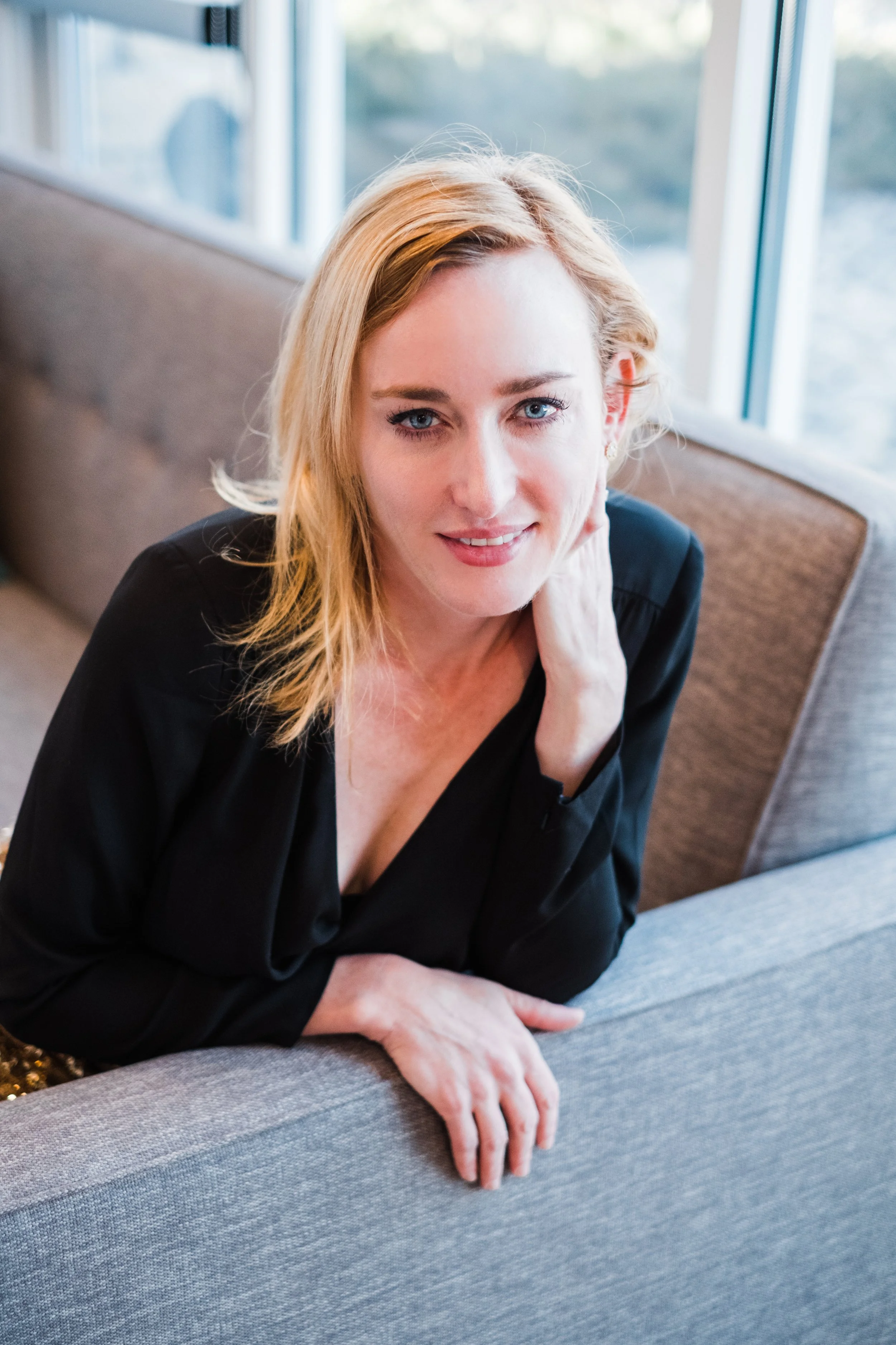 Woman with blonde hair sitting on a gray couch