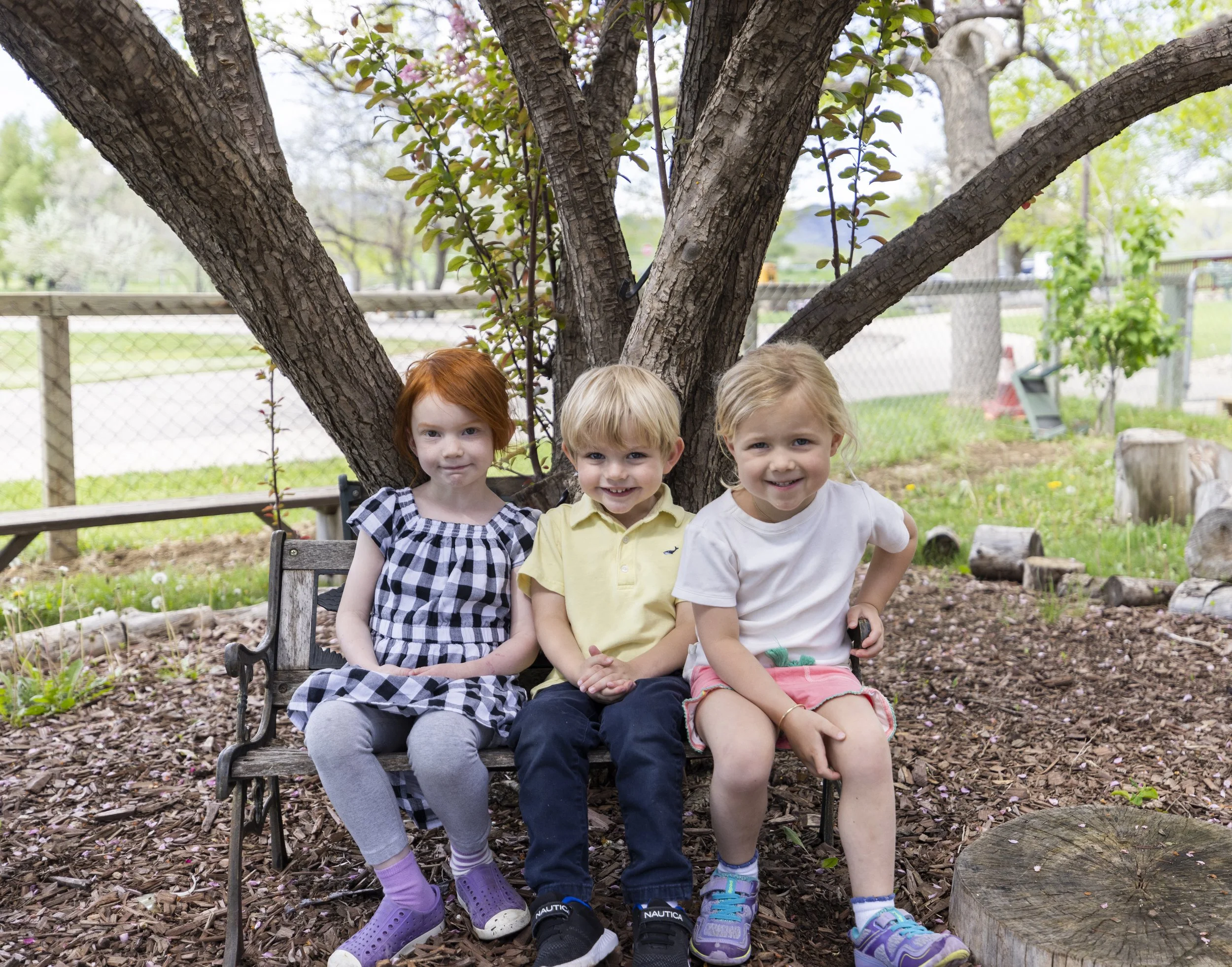 Child drawing at a table in a classroom setting, with colored pencils in a box nearby.