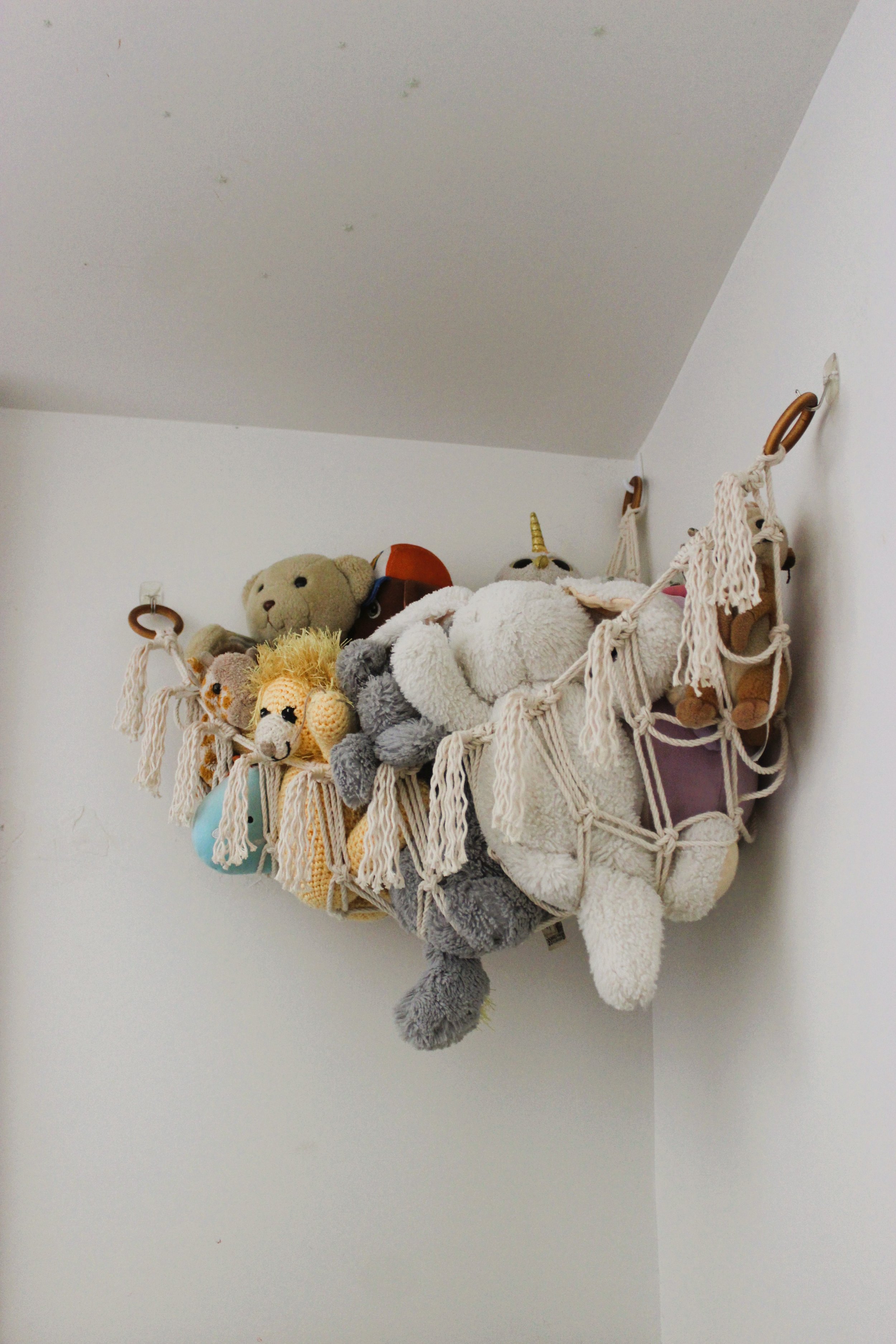 Picture of handmade macrame toy hammock pictured holding lots of stuffed toys