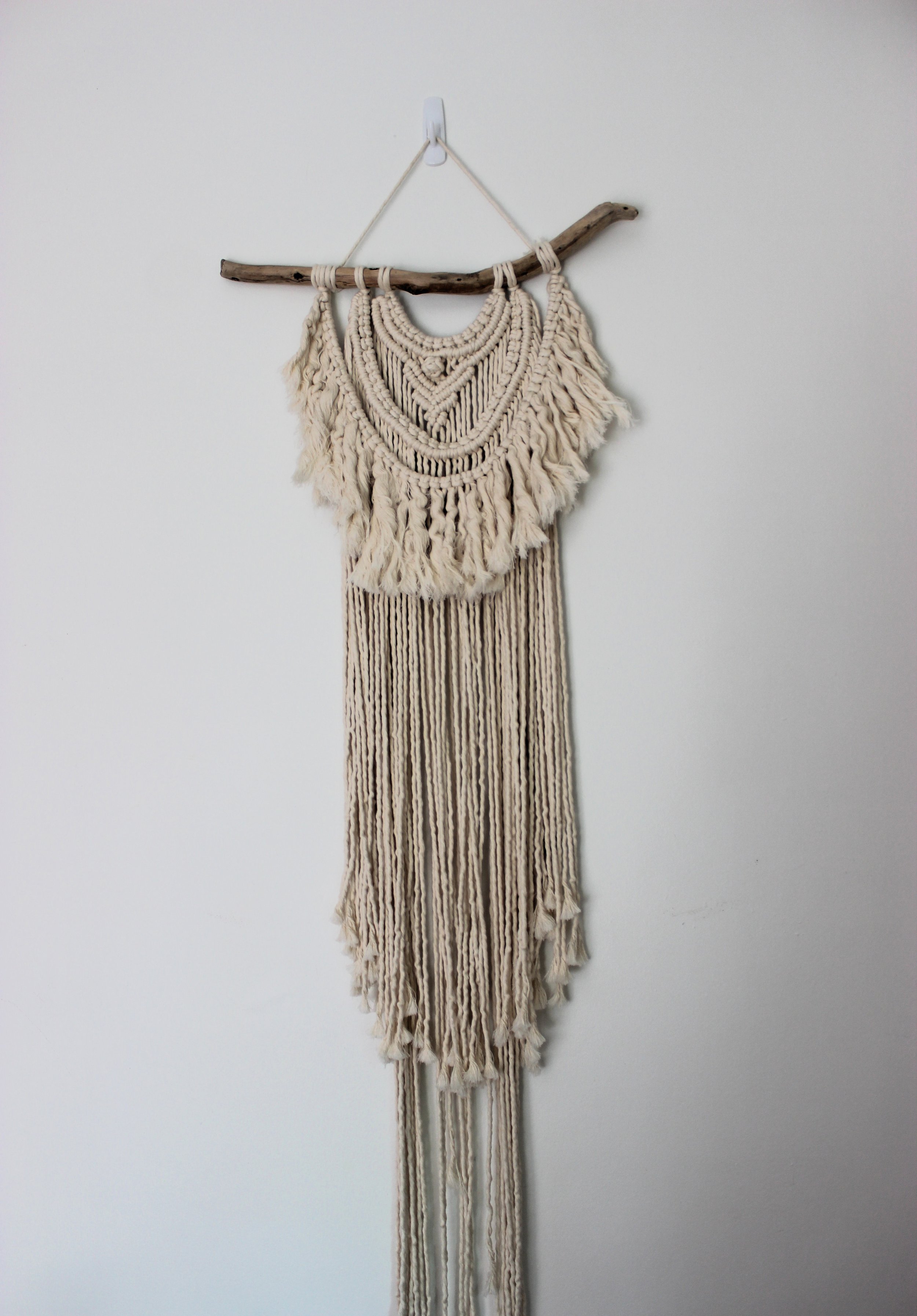 Mystic Macrame Wall Hanging styled on a plain wall showing off its texture and layered components.