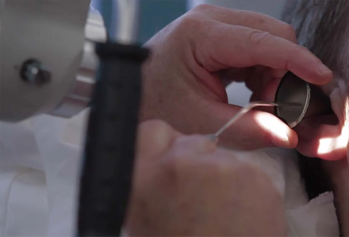 Close-up of a hand performing microsuction to remove ear wax build up from a clients ear.