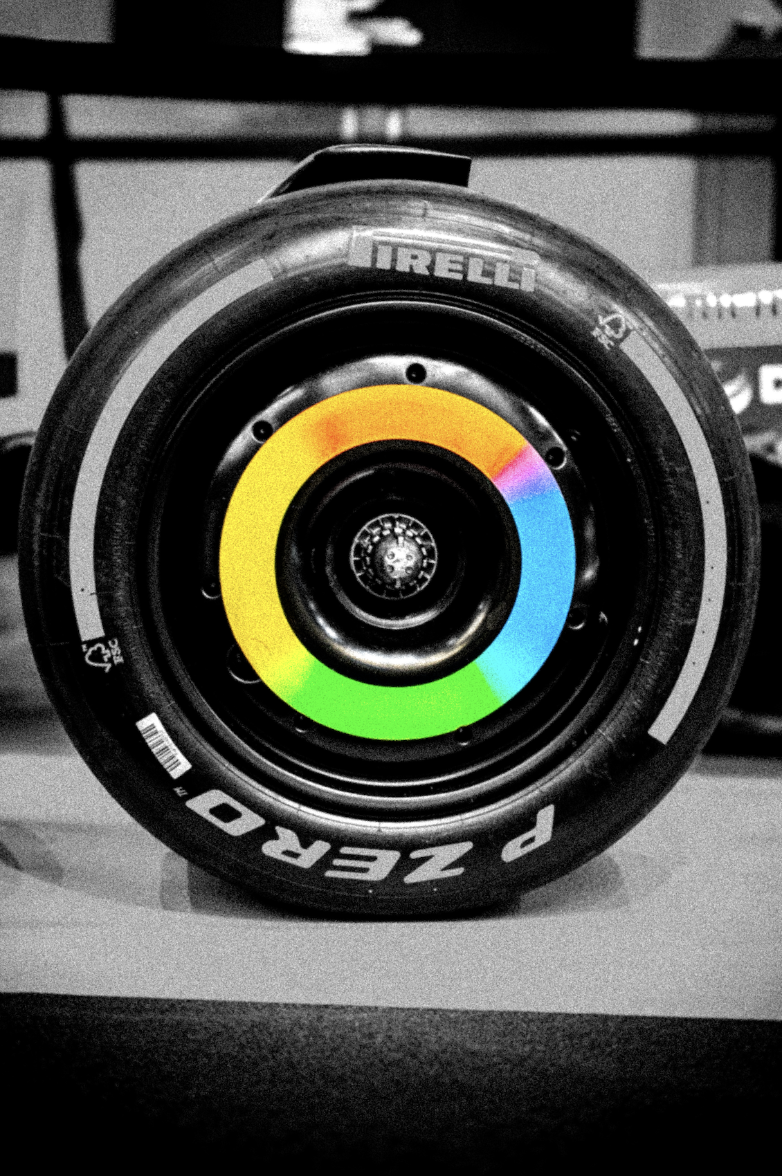 A close-up view of a racing tire with a color calibration chart in the center, black and white background.