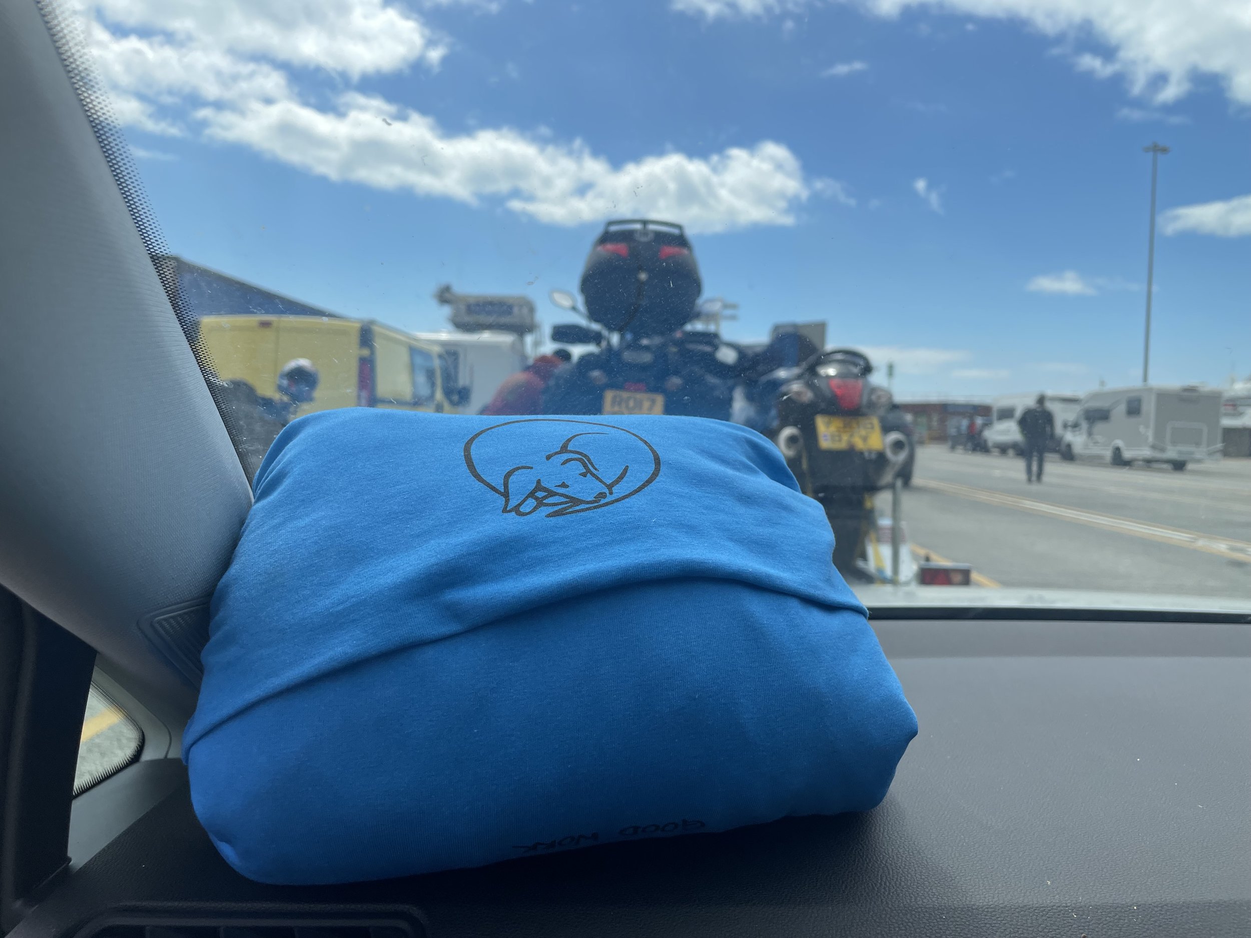 A blue Fold+Rºll on the dashboard of a car - the ferry terminal is visible through the windscreen
