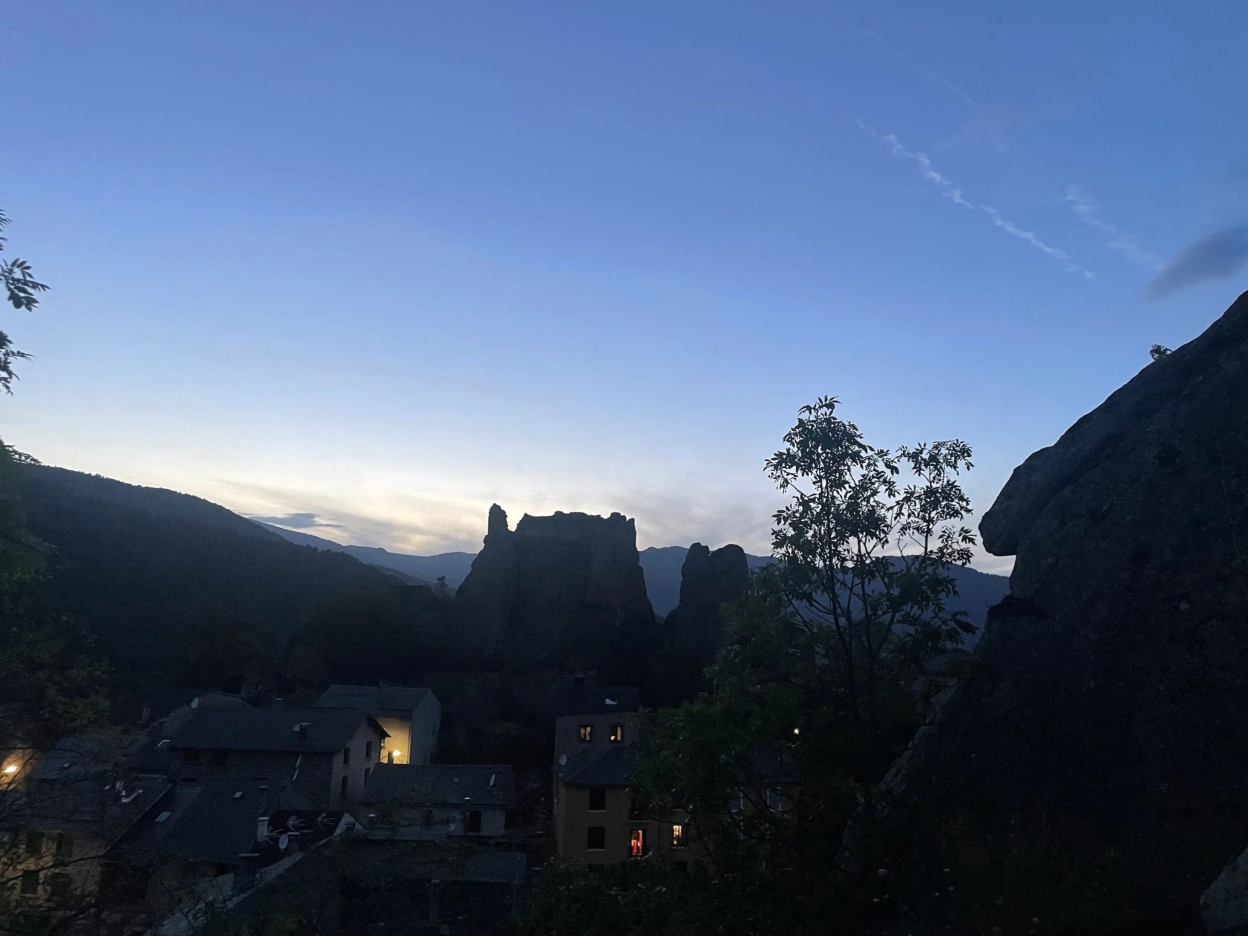The silhouetter of a ruined castle against the evening skyline, with distant mountains