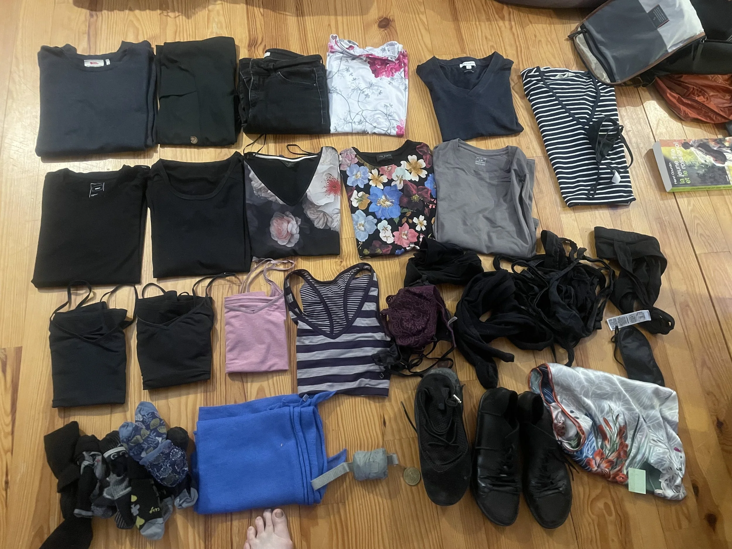 Folded clothes laid out across the floor including underwear and dresses and shoes