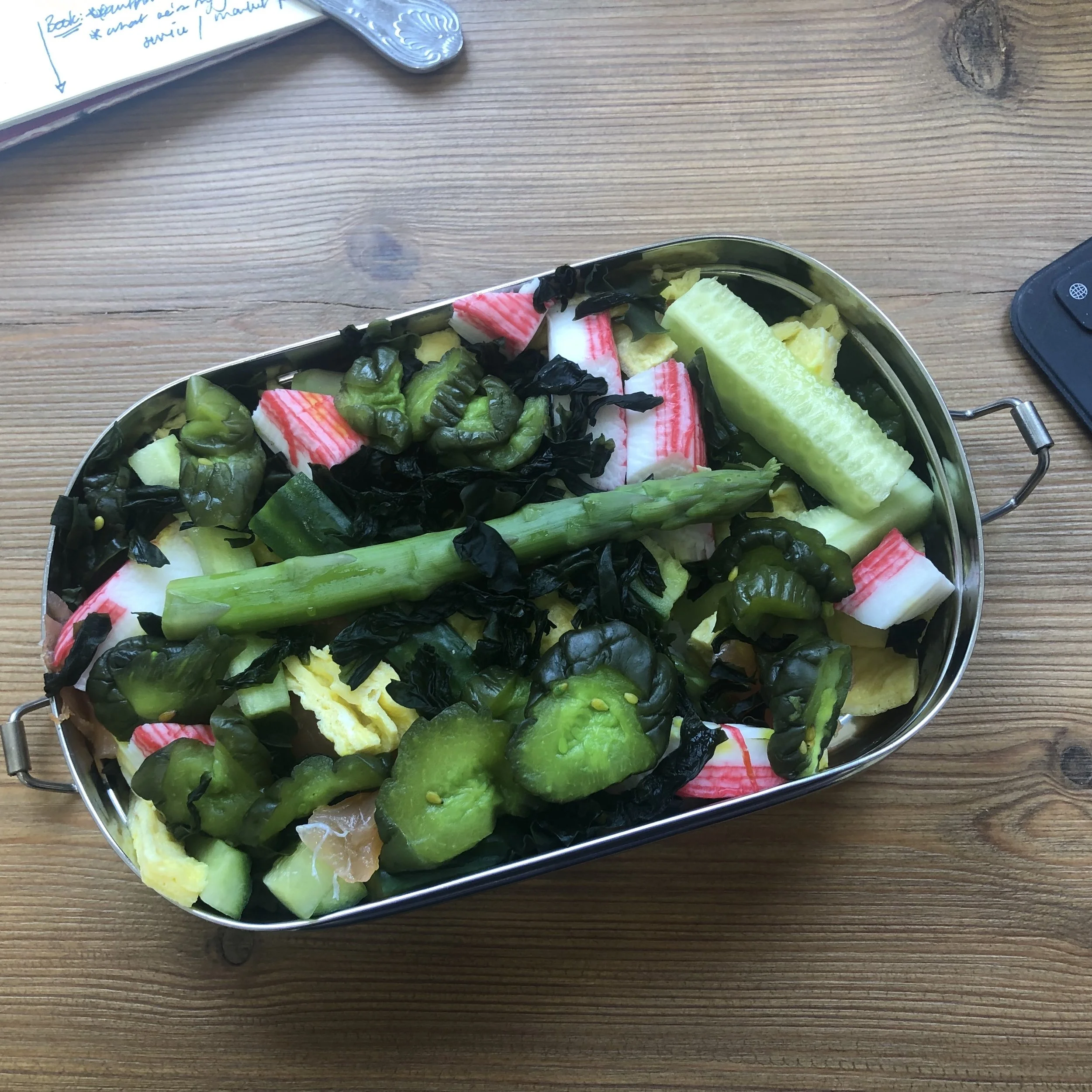 Tin lunch box open containing green salad