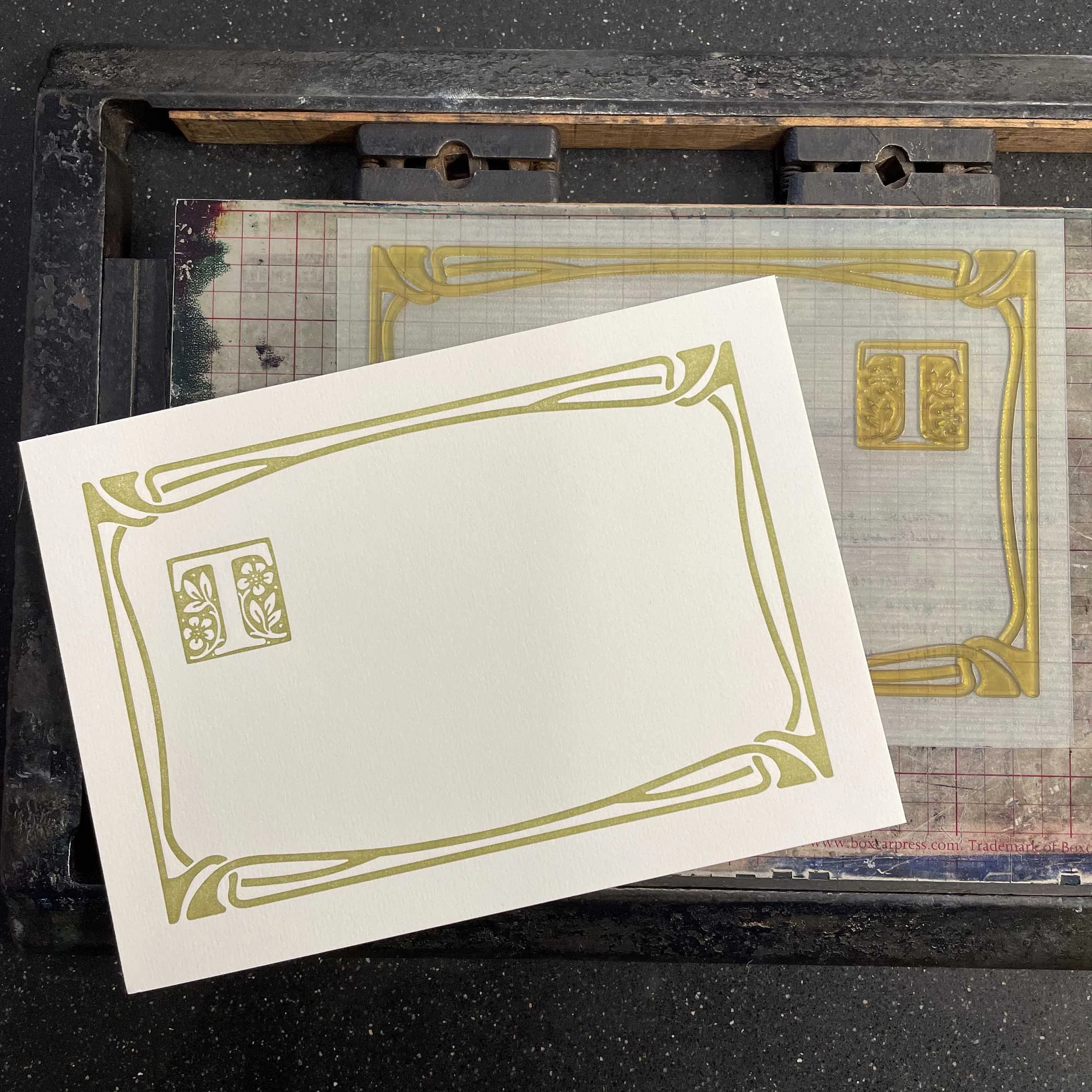 A 5 x 7 letterpress print of a green Art Nouveau style border on white paper. There is also a decorative initial 'T'. The printing plate is shown with the print.