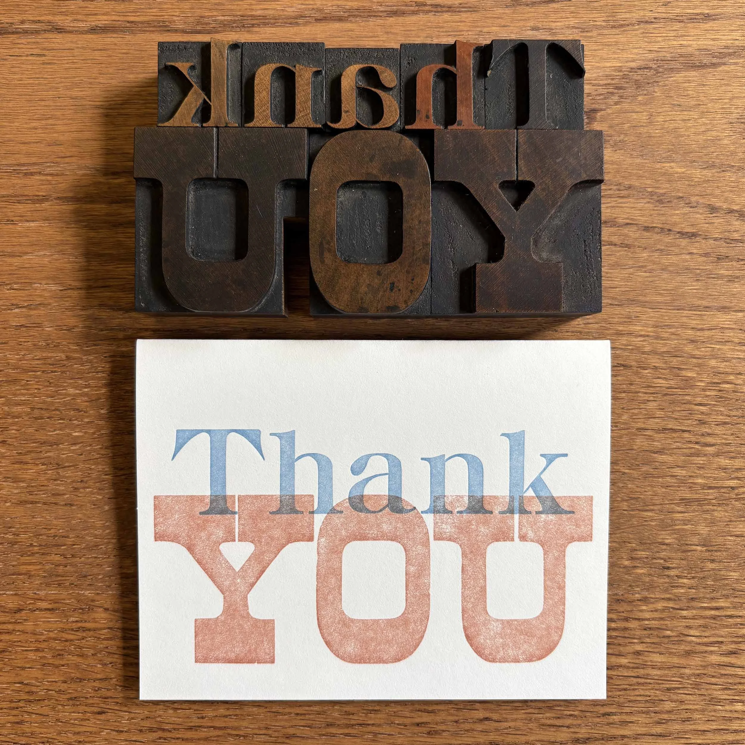 White card with simple type design. 'Thank' letterpress printed in blue and 'YOU' printed in a terracotta color. Matching terracotta envelope. Shown with the antique wood type used in the printing.