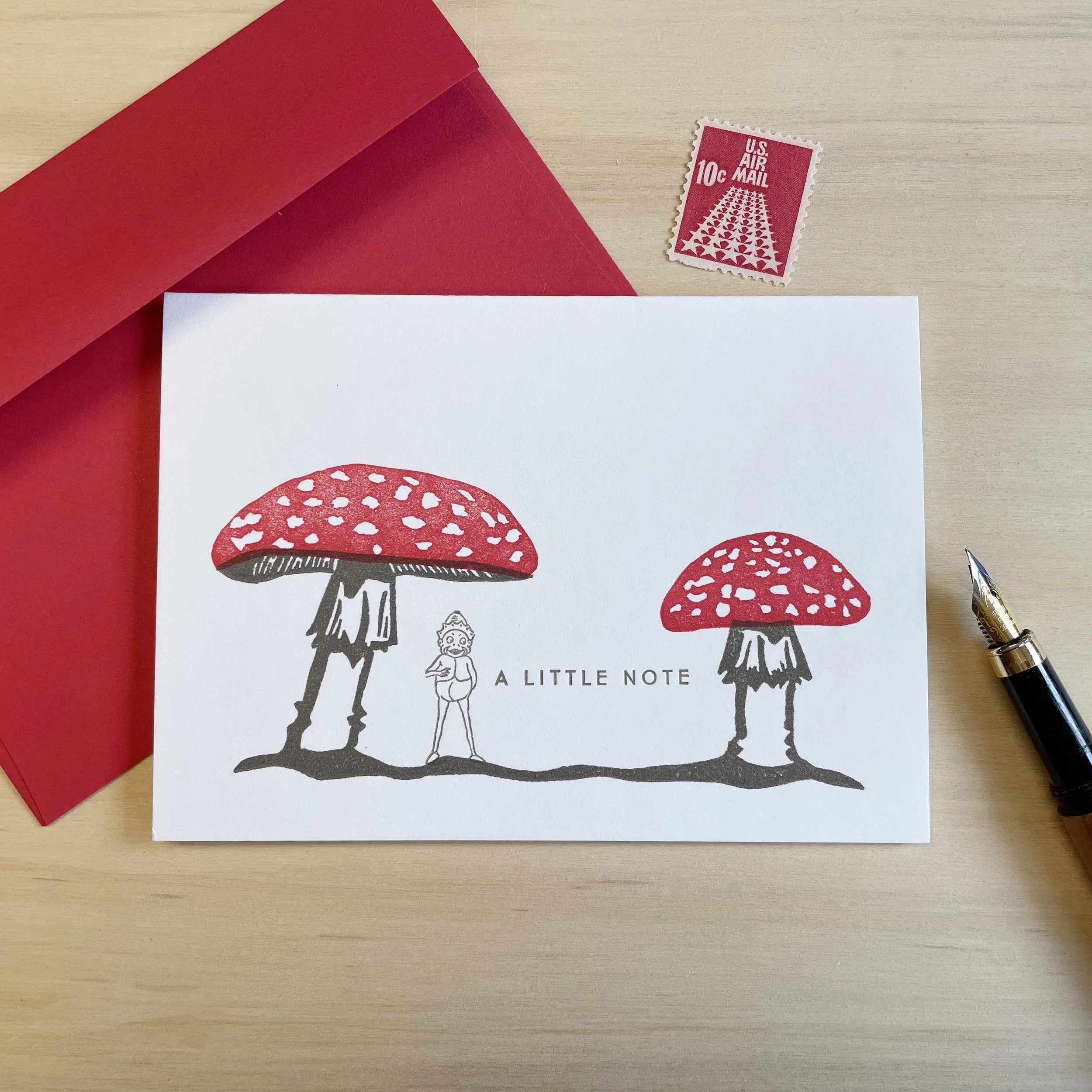 White notecard with illustration of two red capped mushrooms, a Palmer Cox Brownie, and the words A Little Note. Red Envelope.