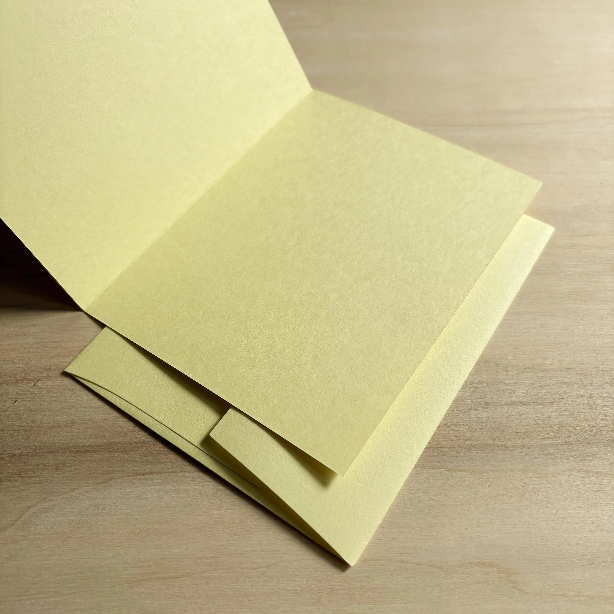 Handmade letterpress card printed on light yellow paper. It's open to show a blank interior. It's resting on a matching yellow envelope with a square flap closure.