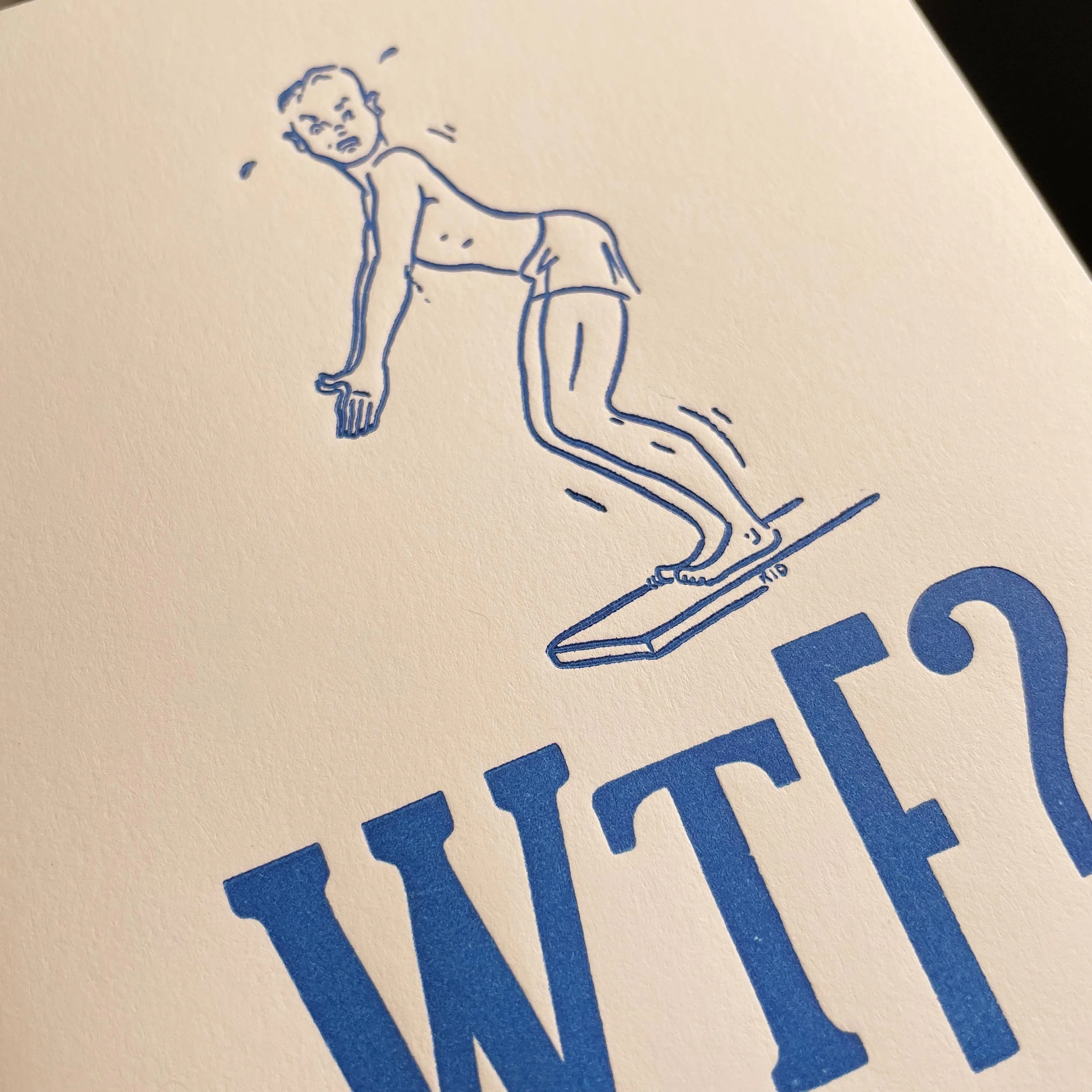 White letterpress card with a cartoonish line drawing of a young man on a diving board with a confused look on his face. Large, mis-matched bold type below says, 'WTF?' Bright blue envelope.