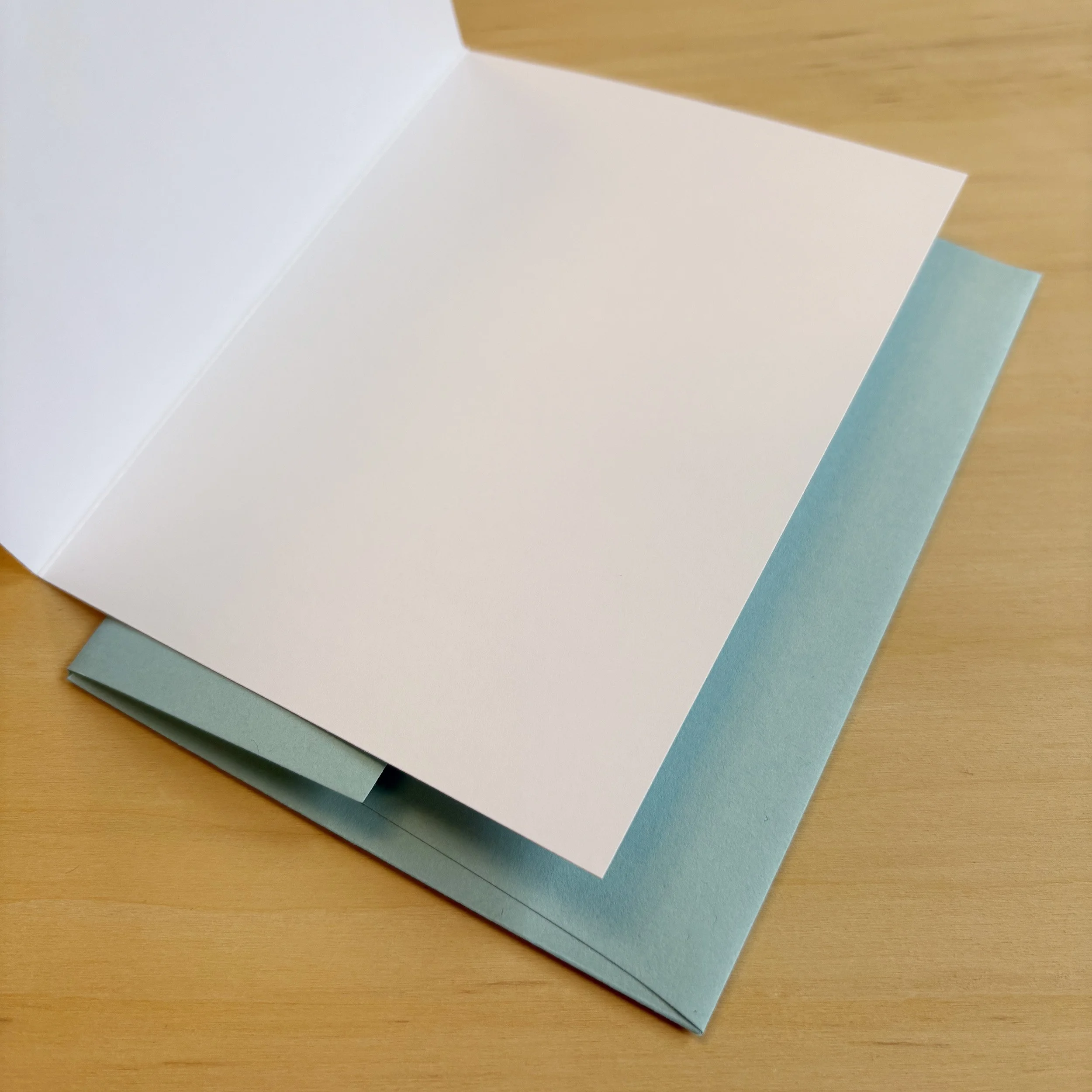 Open card showing blank interior. Crisp white paper. Blue envelope.