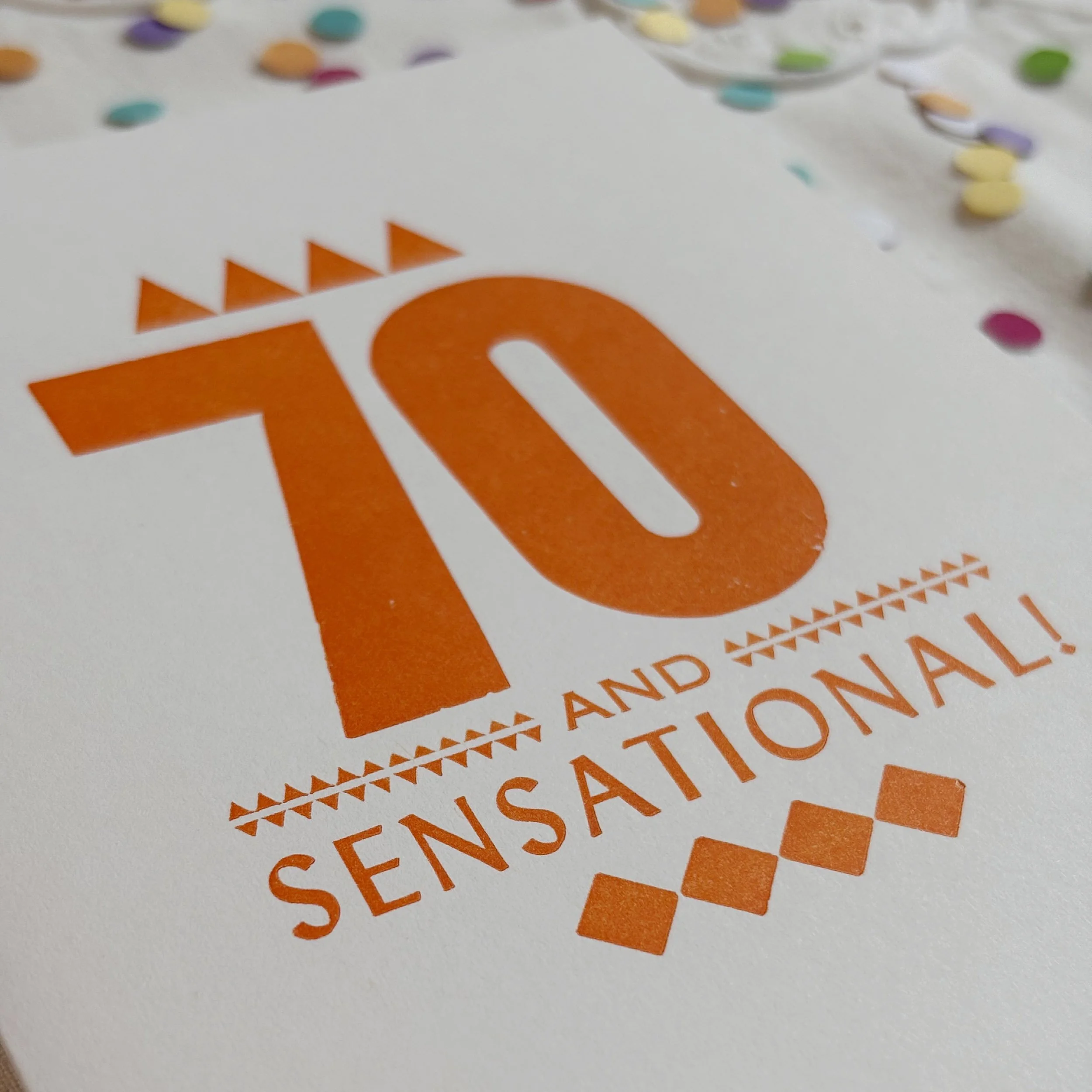 70 and Sensational card features a bold 70 with smaller words AND SENSATIONAL. Letterpress ornaments add decoration. Orange ink on white paper.
