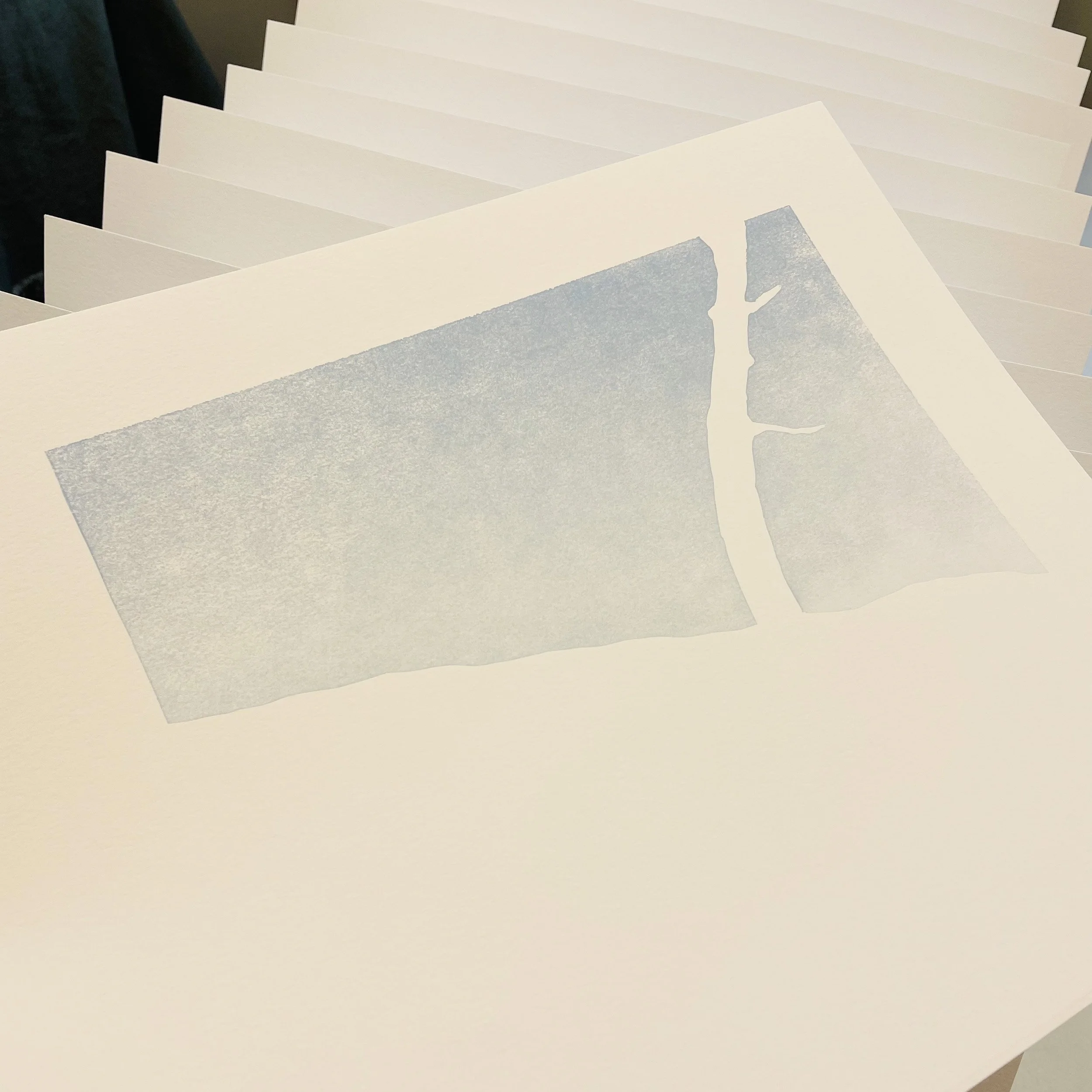 A sheet of white paper printed with sky blue ink. The blue area represents a sky background with the negative white shape of a tree on the far right. The horizon line is angled, sloping to the right.