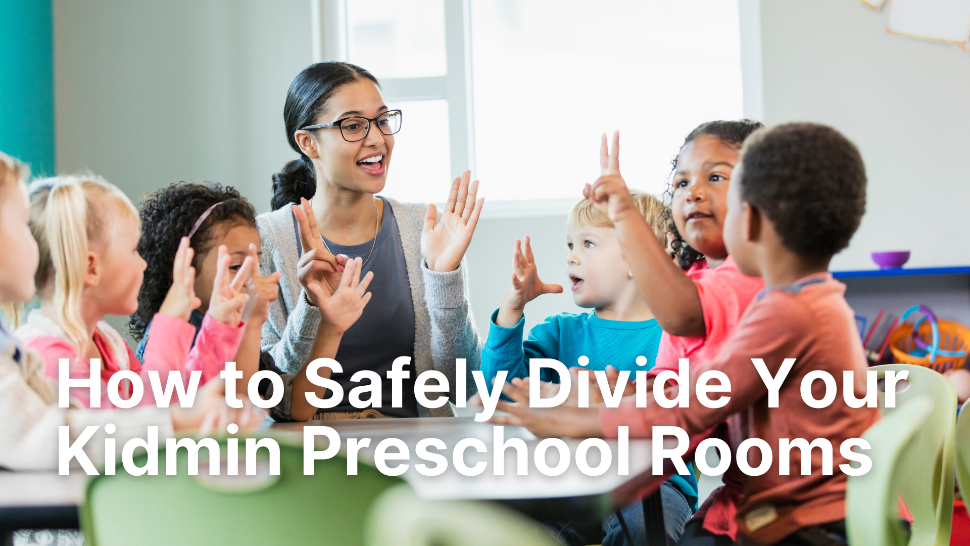A diverse group of young children and their teacher are shown happily and safely engaged at a low table in a bright, modern classroom, with the text overlay 'How to Safely Divide Your Kidmin Preschool Rooms' clearly displayed.
