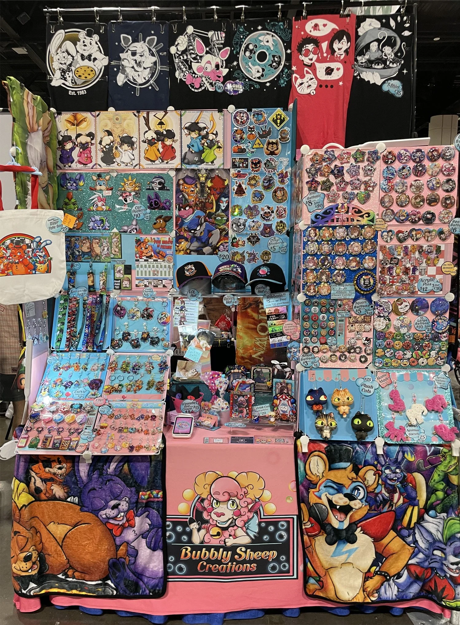 Display of colorful accessories, patches, pins, hats, and bags with cartoon characters and designs at a market stall named Bubbly Sheep Creations.