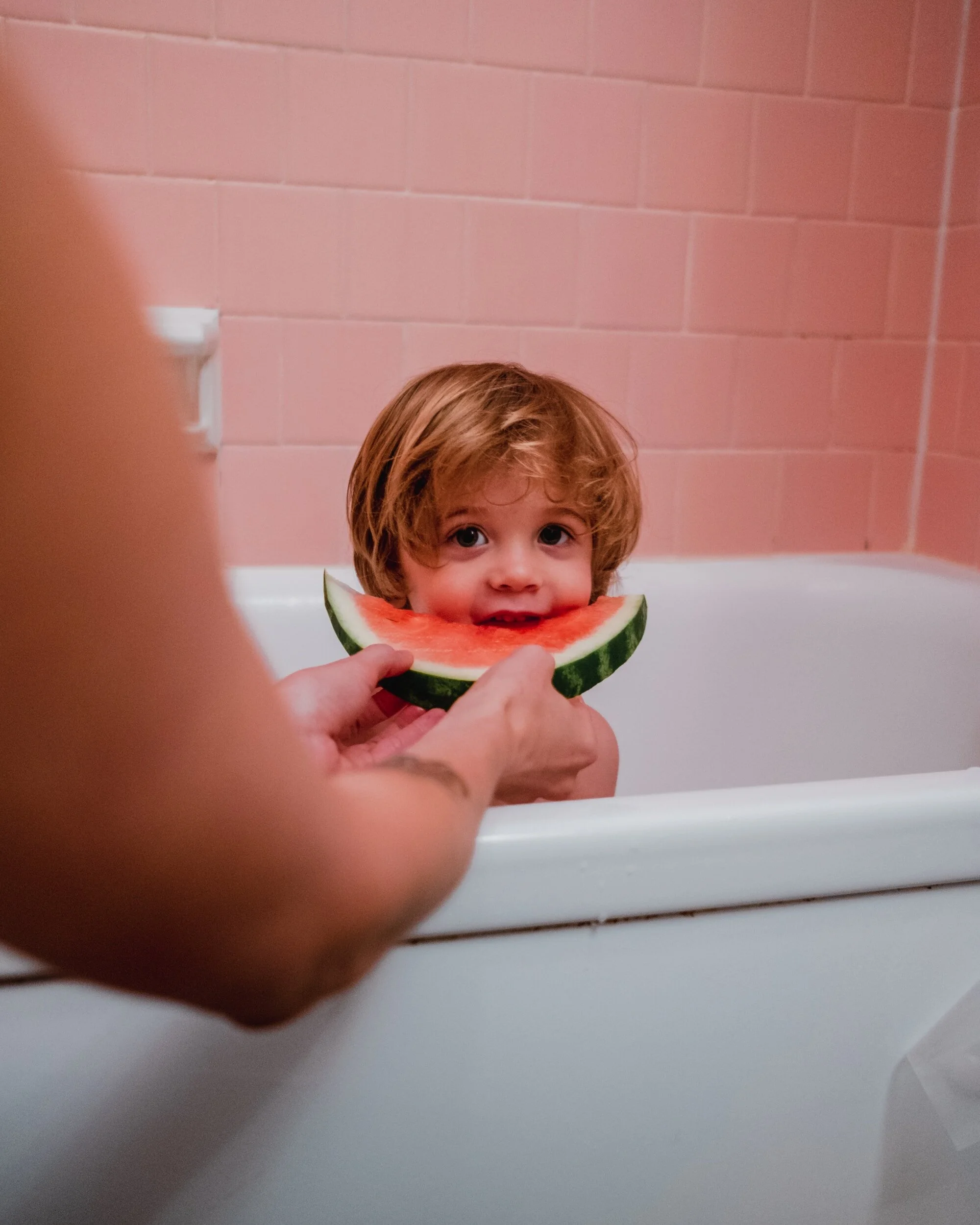 child eating watermelon in the bathtub