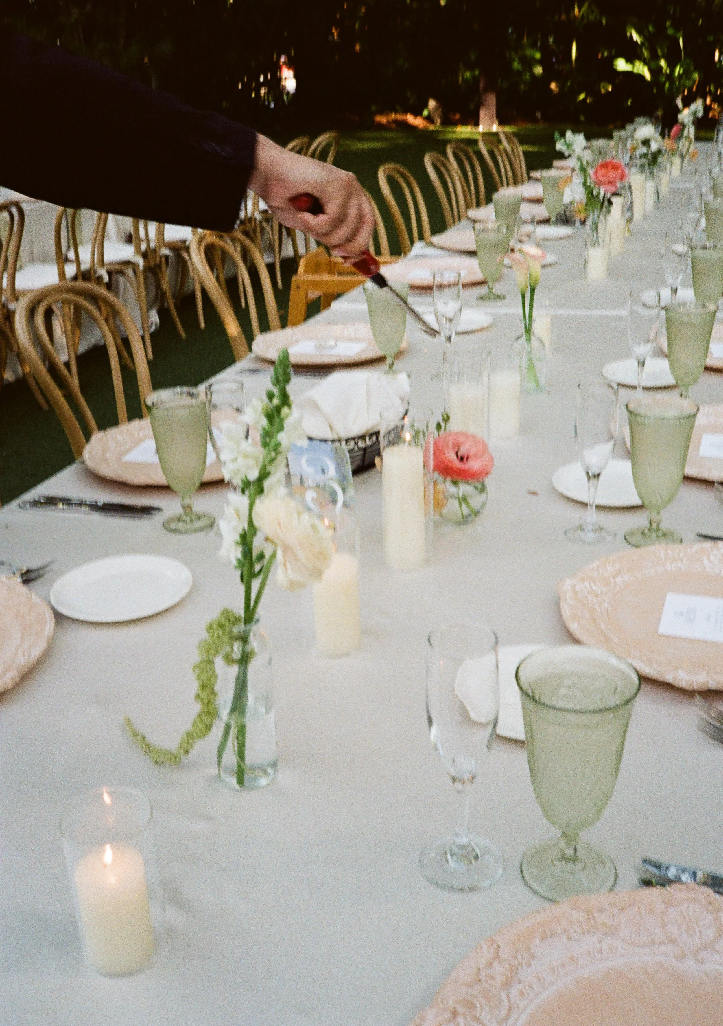 A wedding coordinator at Villa Woodbine, lighting the candles for reception tables