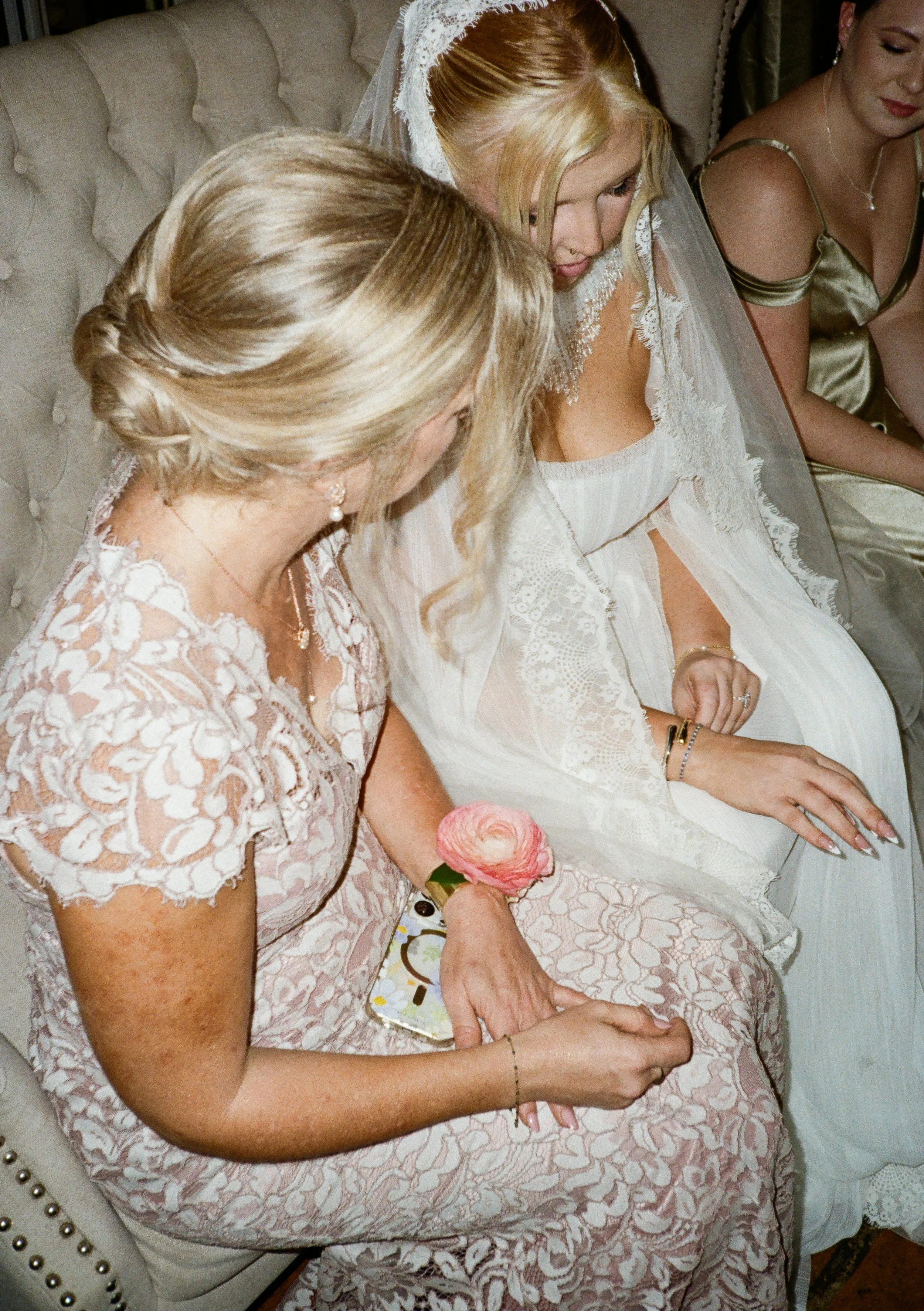Mother wearing her pink corsage during a private moment with her daughter (the bride)